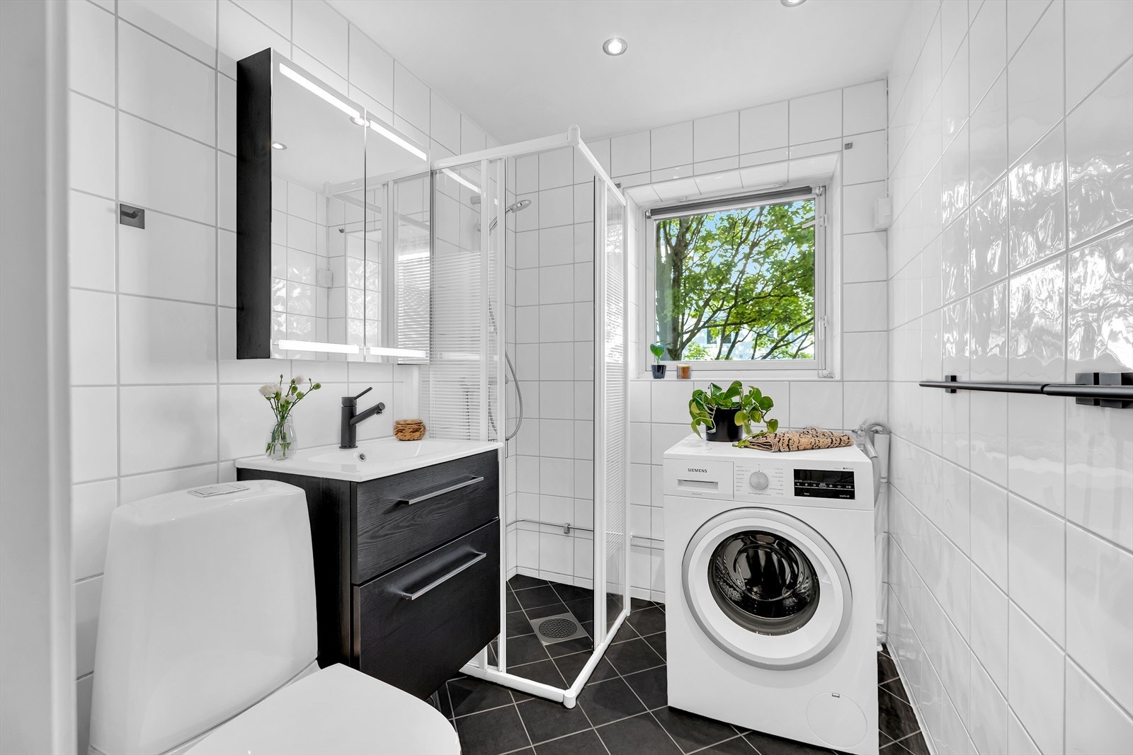 Lyst bad med helflisede overflater, gulvvarme (2017), downlights og opplegg for vaskemaskin Galleribilde