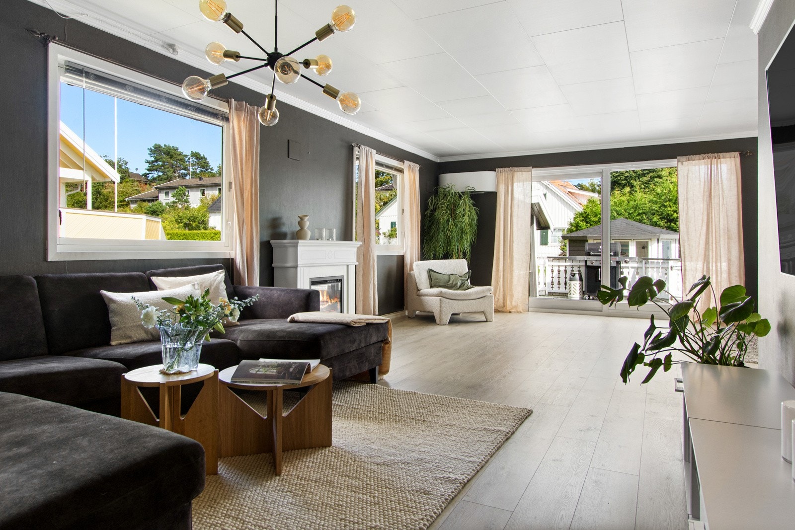 Stuen er et stort, tiltalende rom med laminatgulv, vegger malt i en mørk farge, varmepumpe og doble franske dører til kjøkkenet. Galleribilde