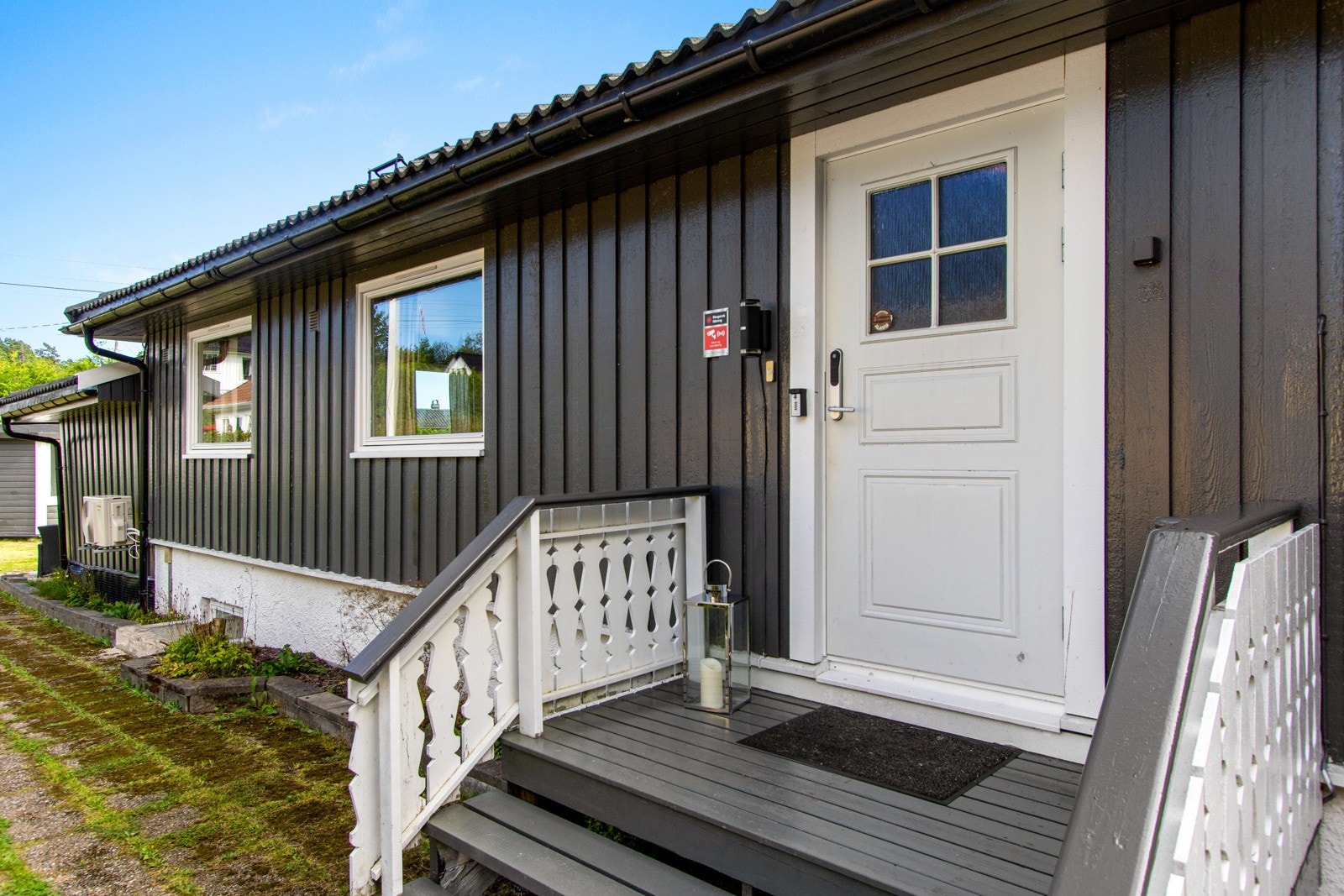 I bakkant av boligen er det et pent inngangsparti til første etasje med malt trapp, rekkverk på begge sider og hvit inngangsdør med innfelt glassparti. Galleribilde