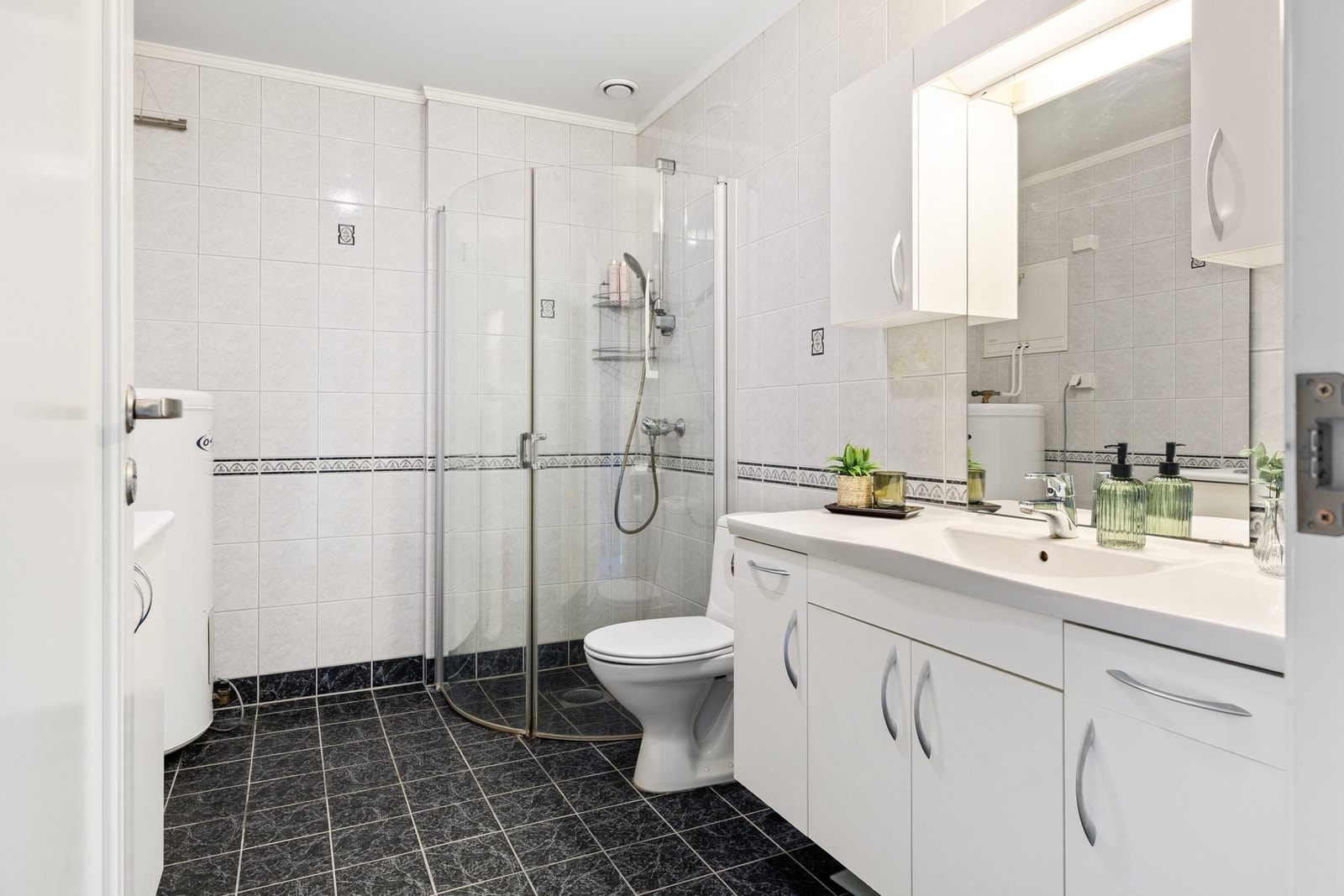 Kombinert bad/vaskerom med flislagt gulvoverflate med gulvvarme, og fliskledde vegger Galleribilde