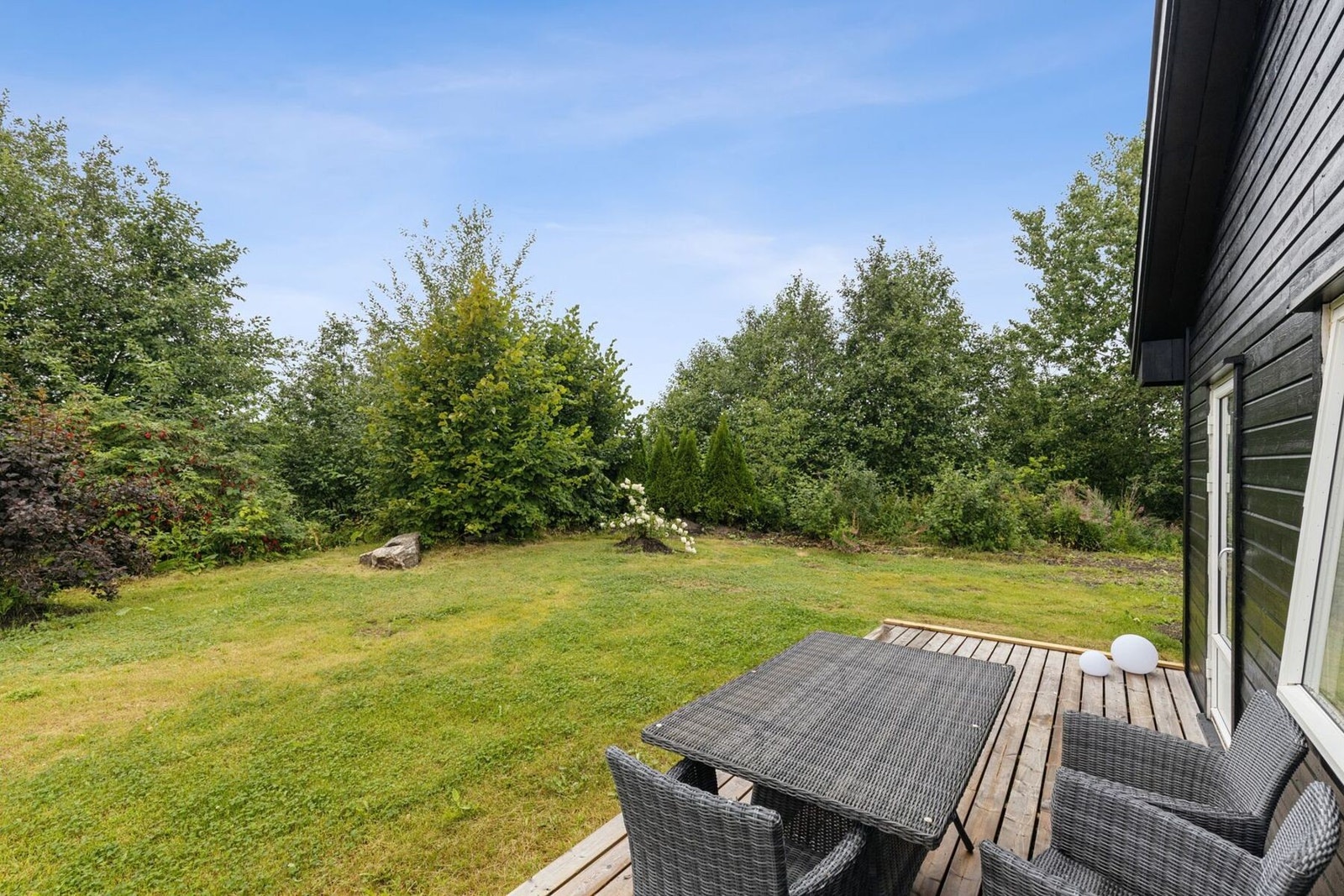 Hagen er delvis opparbeidet med plen og omkranset av vegetasjon som skaper en grønn og skjermet ramme rundt eiendommen. Galleribilde