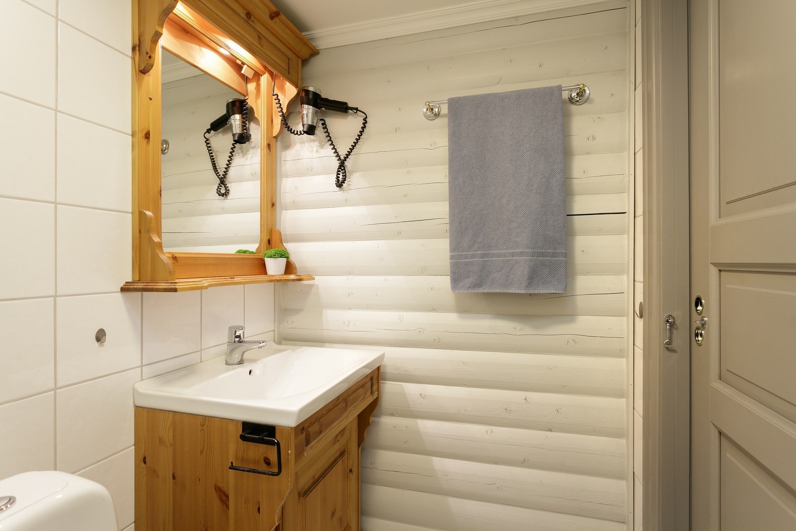 Bad har flislagt gulv med gulvvarme, malte tømmervegger, fliser på vegg i dusjsone. Wc, dusjvegg og innredning med servant. Galleribilde