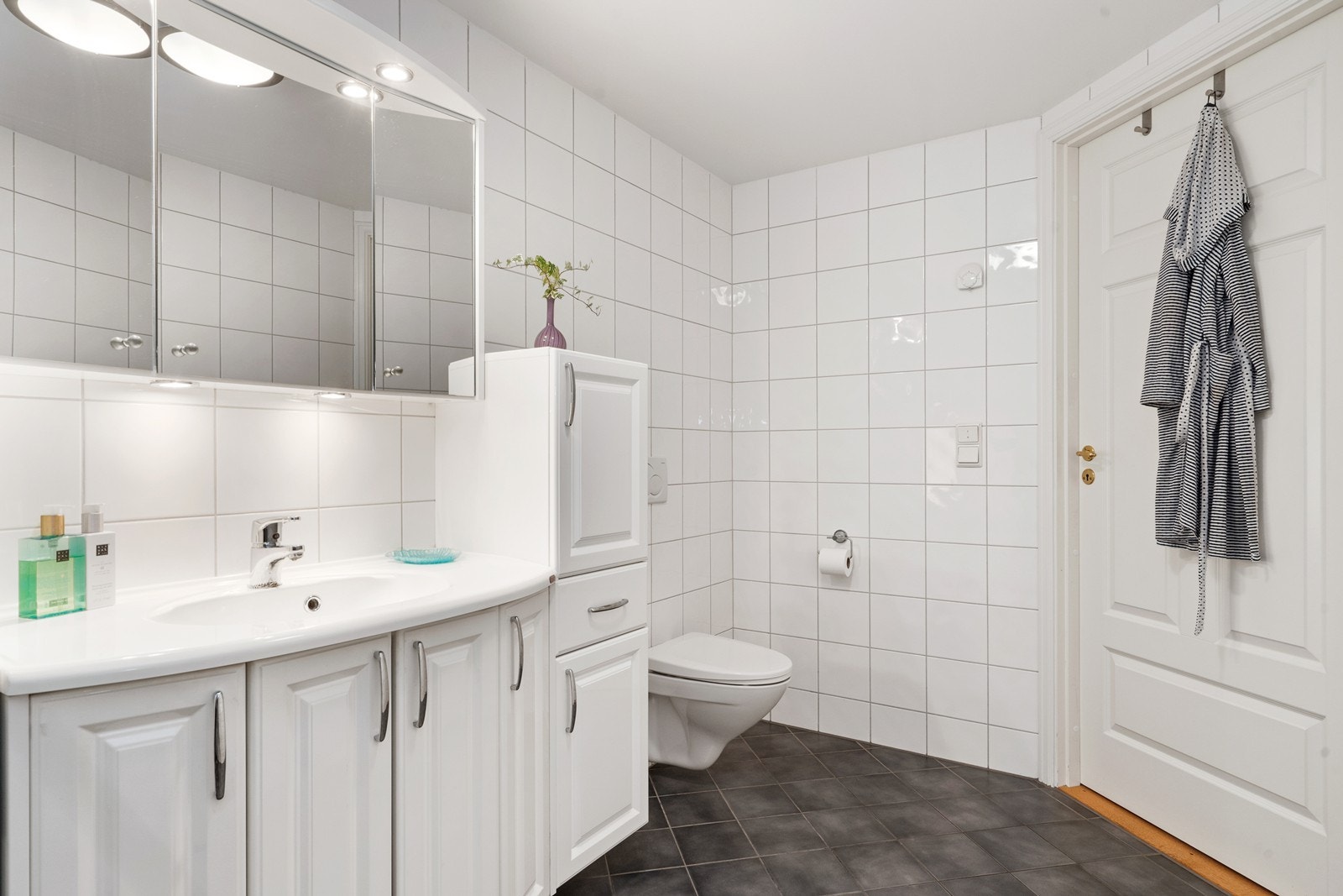 Badet har gråtonede fliser på gulv og hvite fliser på vegg. Galleribilde