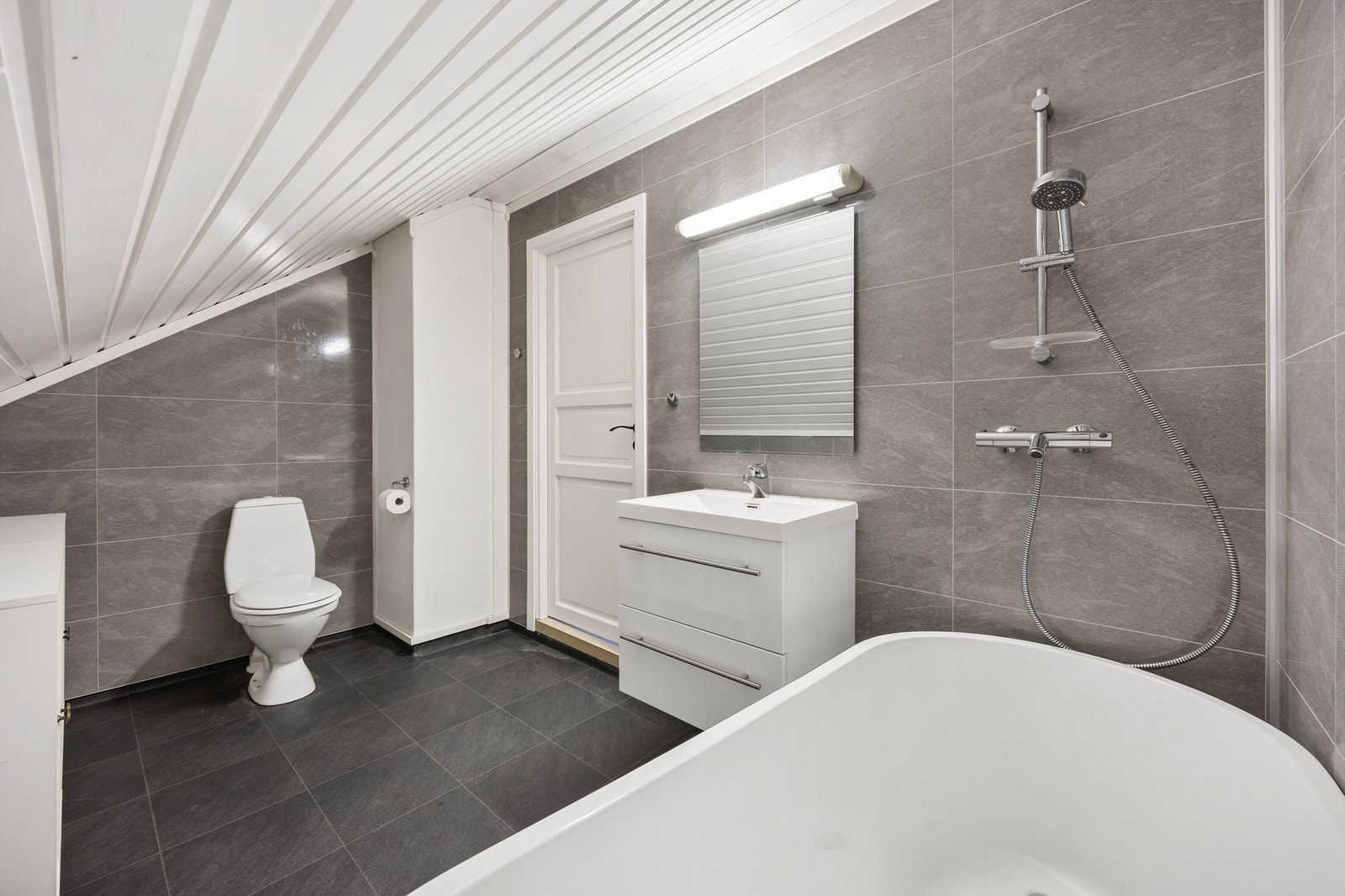 Moderne bad oppusset i 2018 med badekar, speil med belysning og servant med underskap Galleribilde