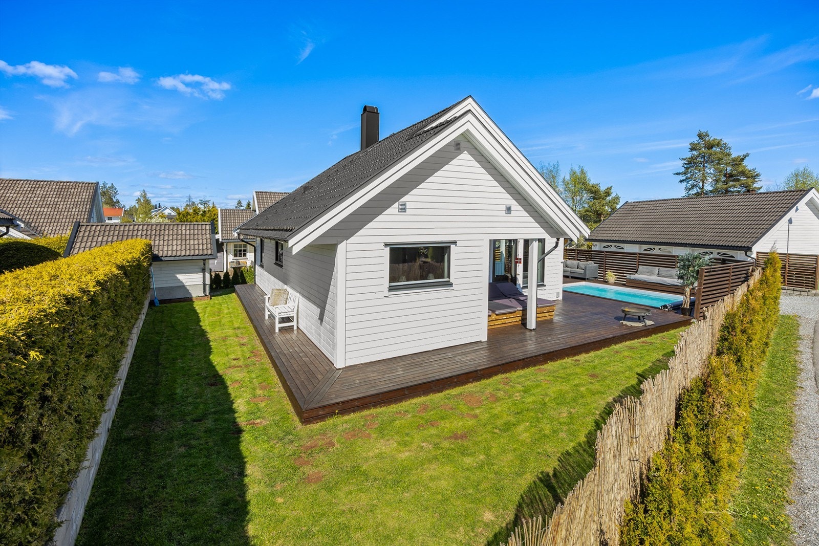Tomten er fint opparbeidet med gressplen og stor terrasse på ca 60 kvm samt oppvarmet basseng med diverse sittegrupper rundt Galleribilde