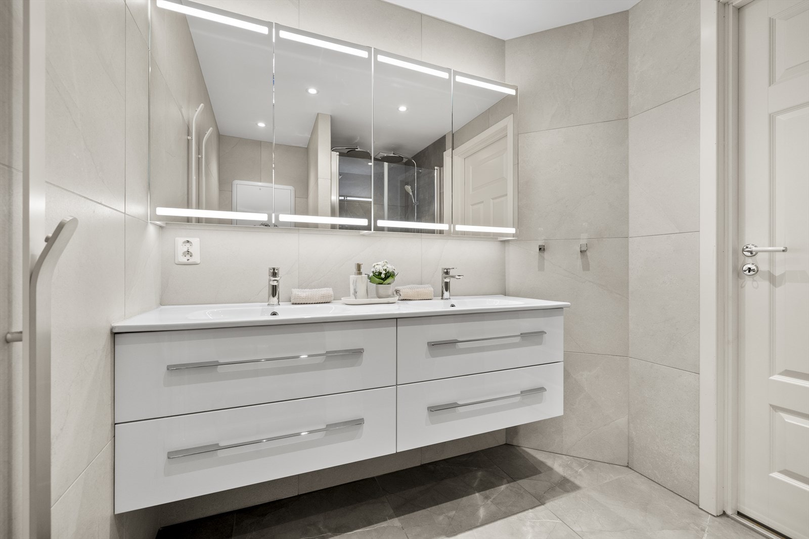 Badet innehar vegghengt toalett, dobbelservant med skuffer og dusjnisje med dobbeldusj og glassdører. Galleribilde