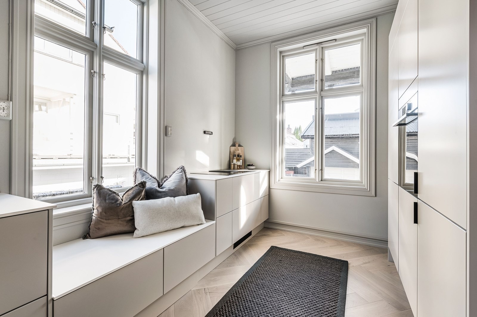 Kjøkkenet fremstår stilrent og moderne, med laminerte skrog, en eksklusiv benkeplate i kompositt/stein og integrerte hvitevarer som gir et helhetlig uttrykk Galleribilde