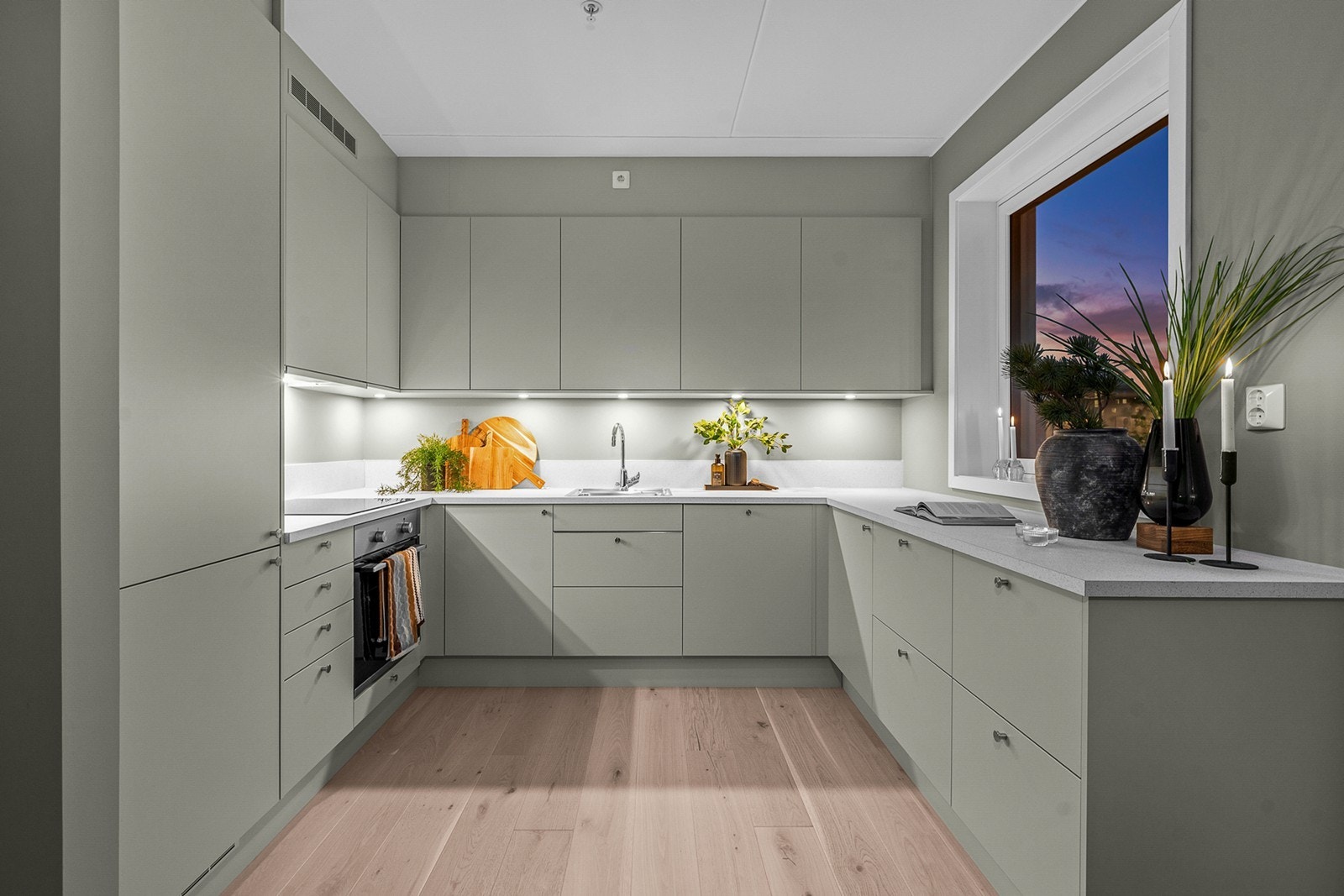 Kjøkkenet er stilrent utformet med laminatbenkeplate og utenpåliggende spotter under overskap som gir både godt arbeidslys og en lun stemning Galleribilde