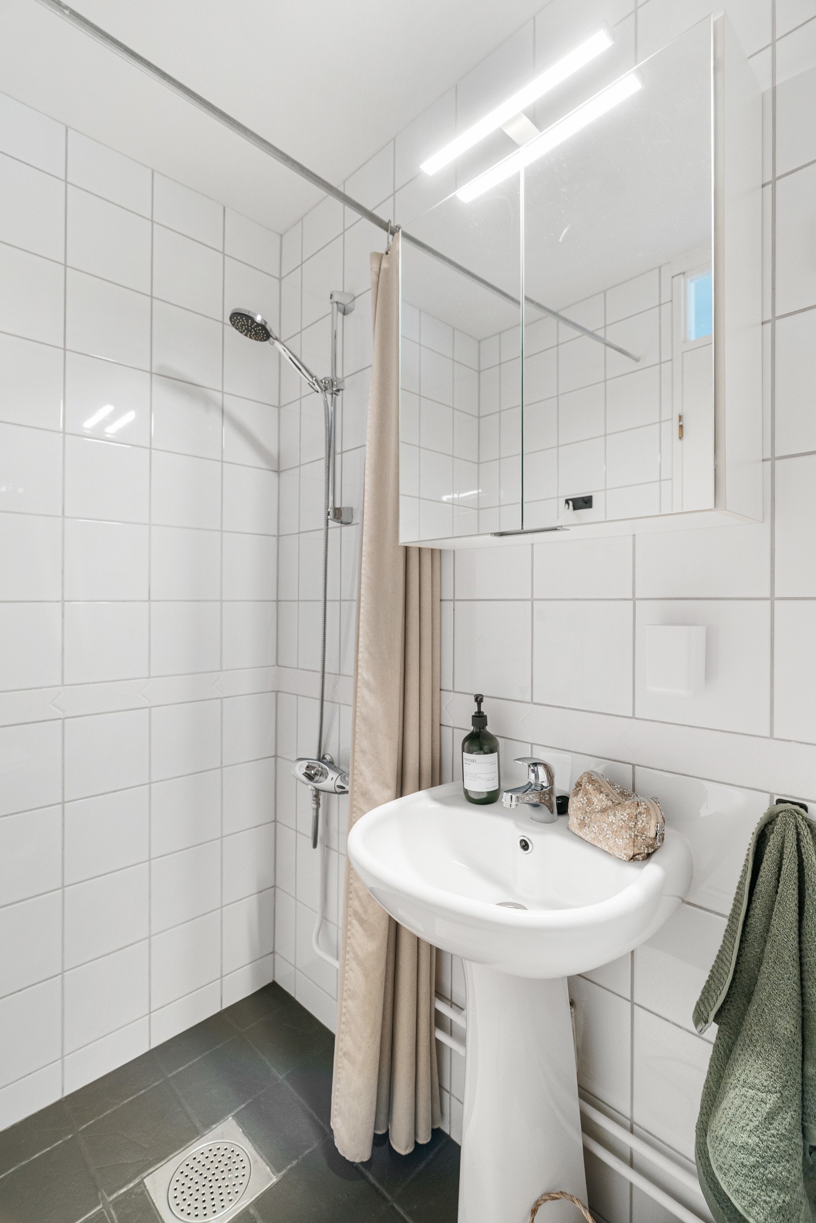 Badet er utstyrt med servant, speilskap, belysning, dusjgarnityr og toalett Galleribilde