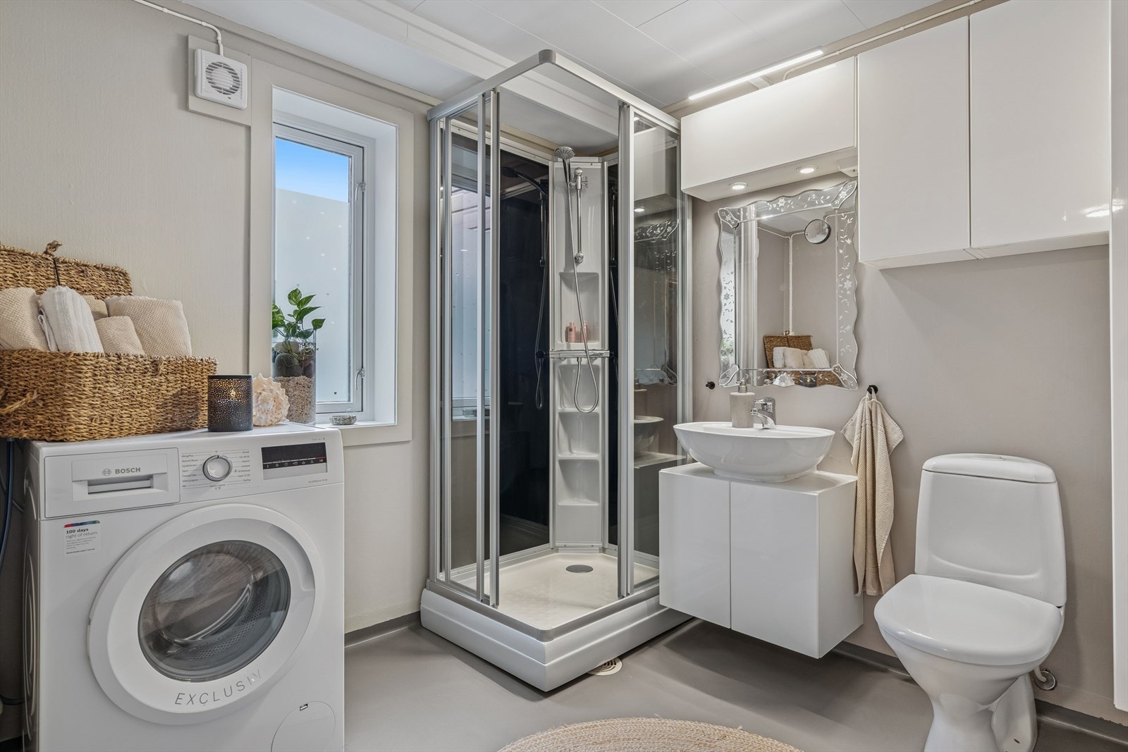 Badet er av eldre dato med vinyl på gulv og vegger med malerstrie - Her finner du dusjkabinett (fra 2025), toalett, baderomsinnredning og opplegg for vaskemaskin Galleribilde