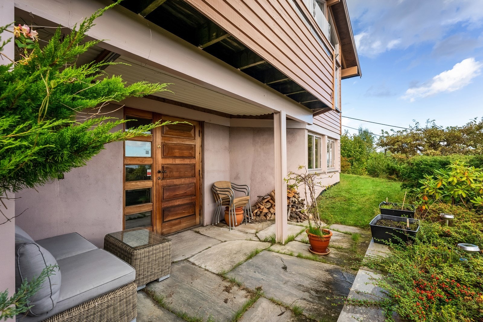 Steinlagt, delvis overbygget uteareal på bakkeplan mot sør. Galleribilde