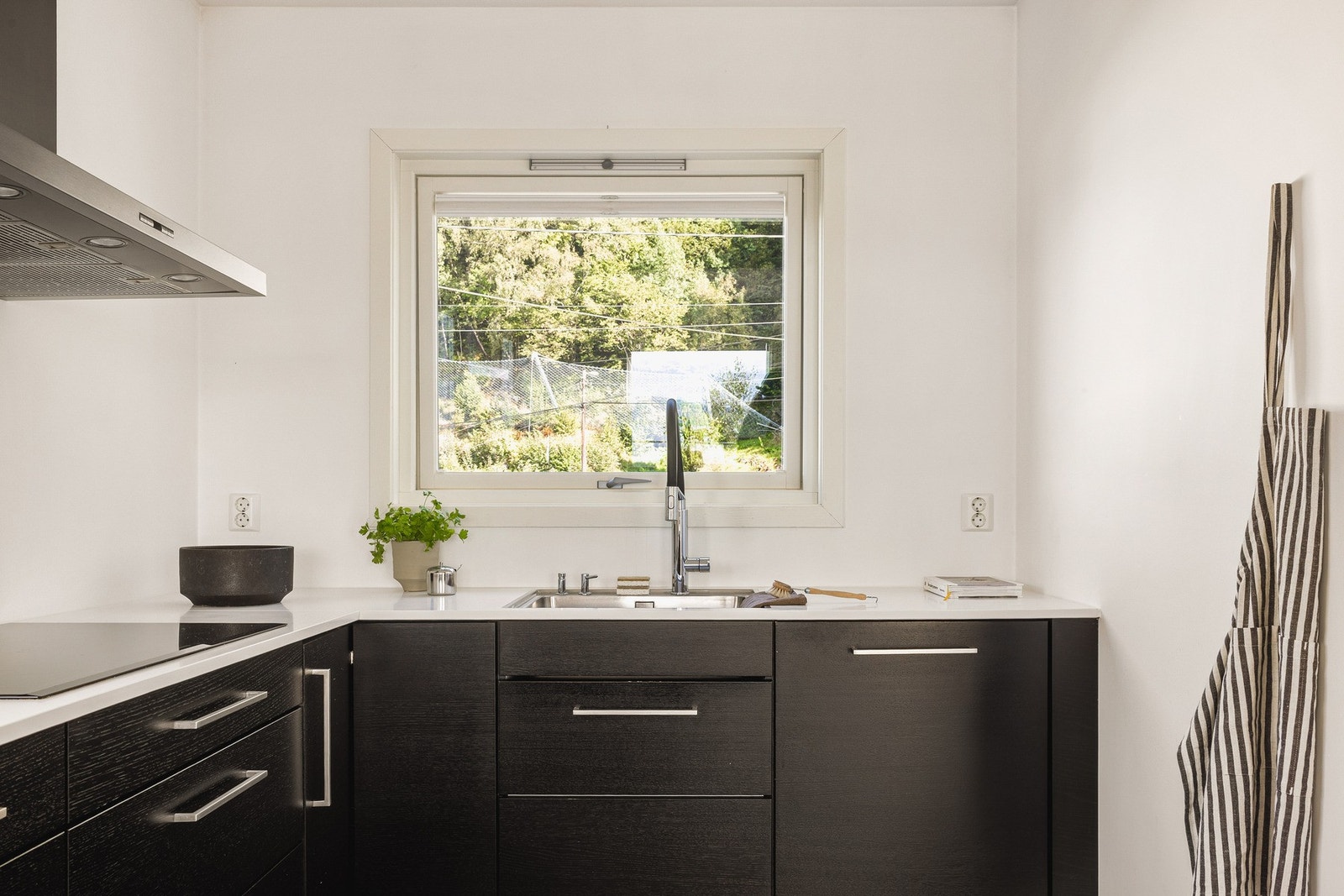 Stilrent kjøkken med slette fronter og hvit steinbenkeplate. Galleribilde