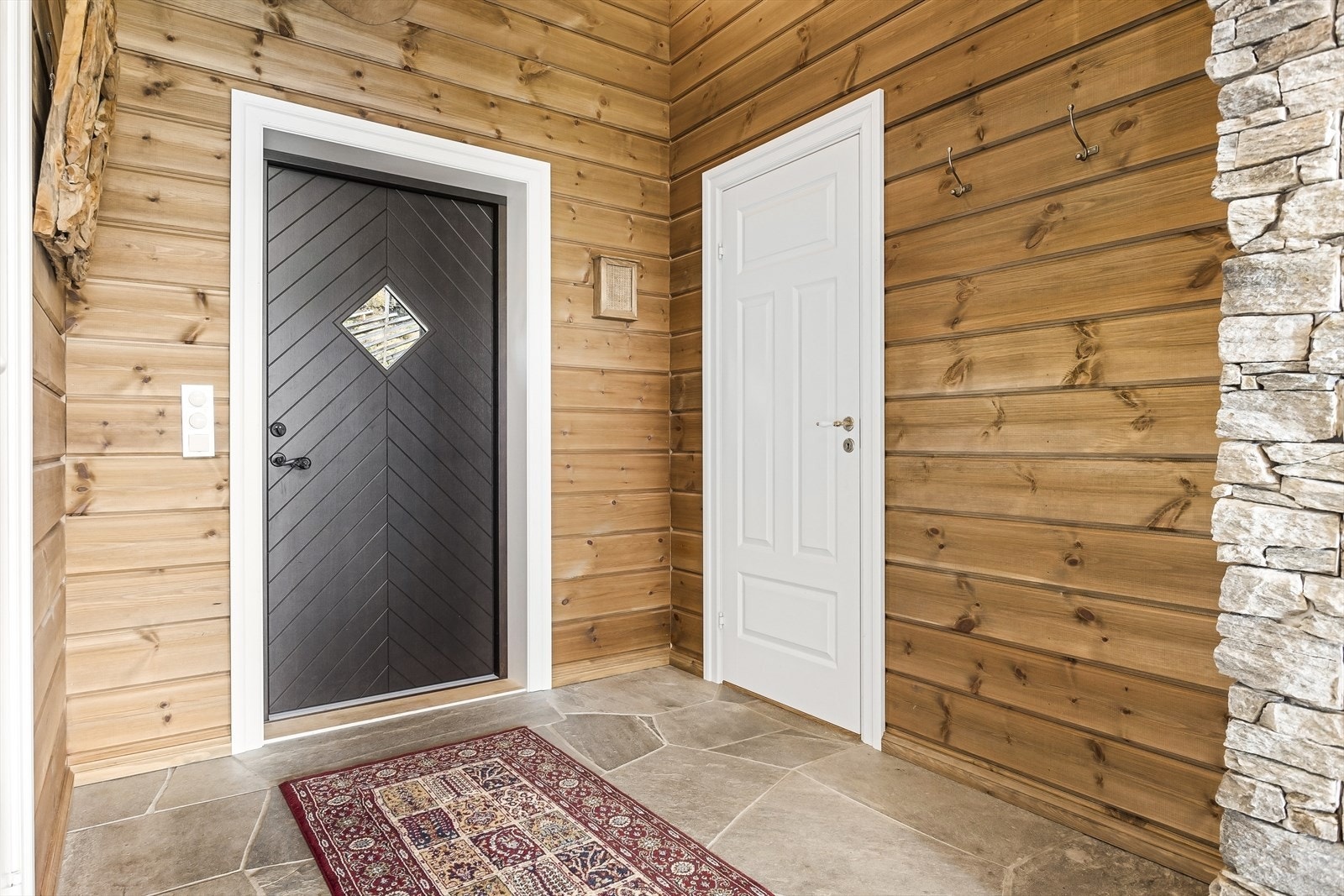 Velkommen inn i en romslig entré med et flott skifergulv og god plass til å henge fra seg yttertøy. Galleribilde