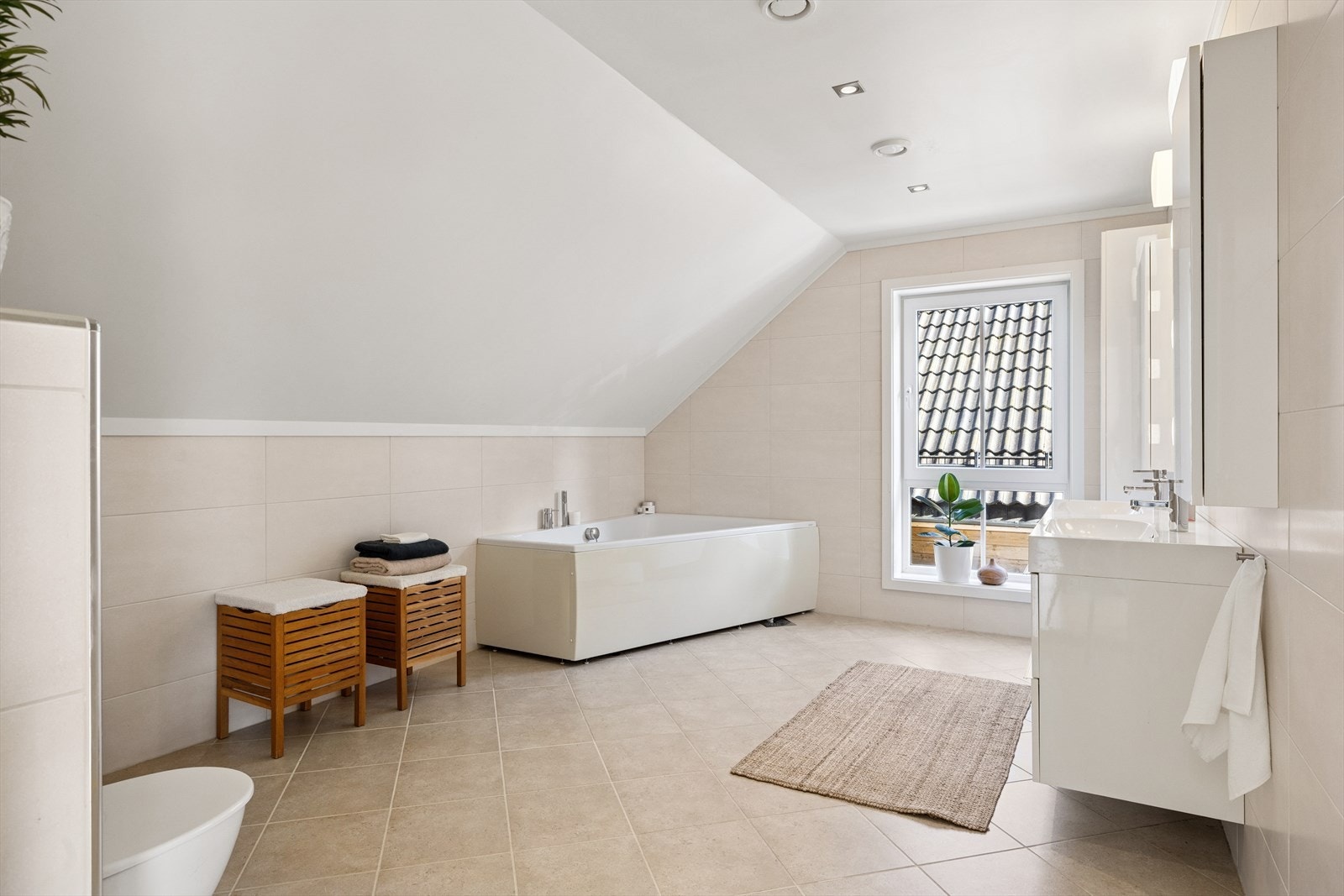 Badet i andre etasje har enkel tilkomst til soverommene og er lekkert innredet med dobbelt servant som står i fin stil til de store, duse flisene. Galleribilde