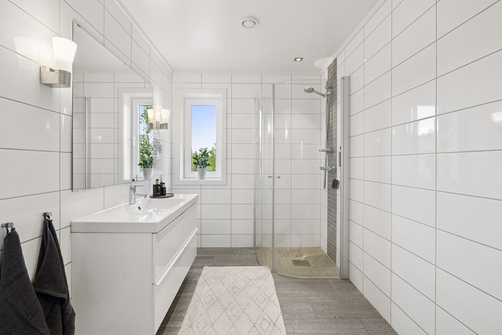 Badet i første etasje har flislagte gulv og vegger og baderomsinnredning som består av vask, vegghengt toalett og dusjhjørne. Galleribilde