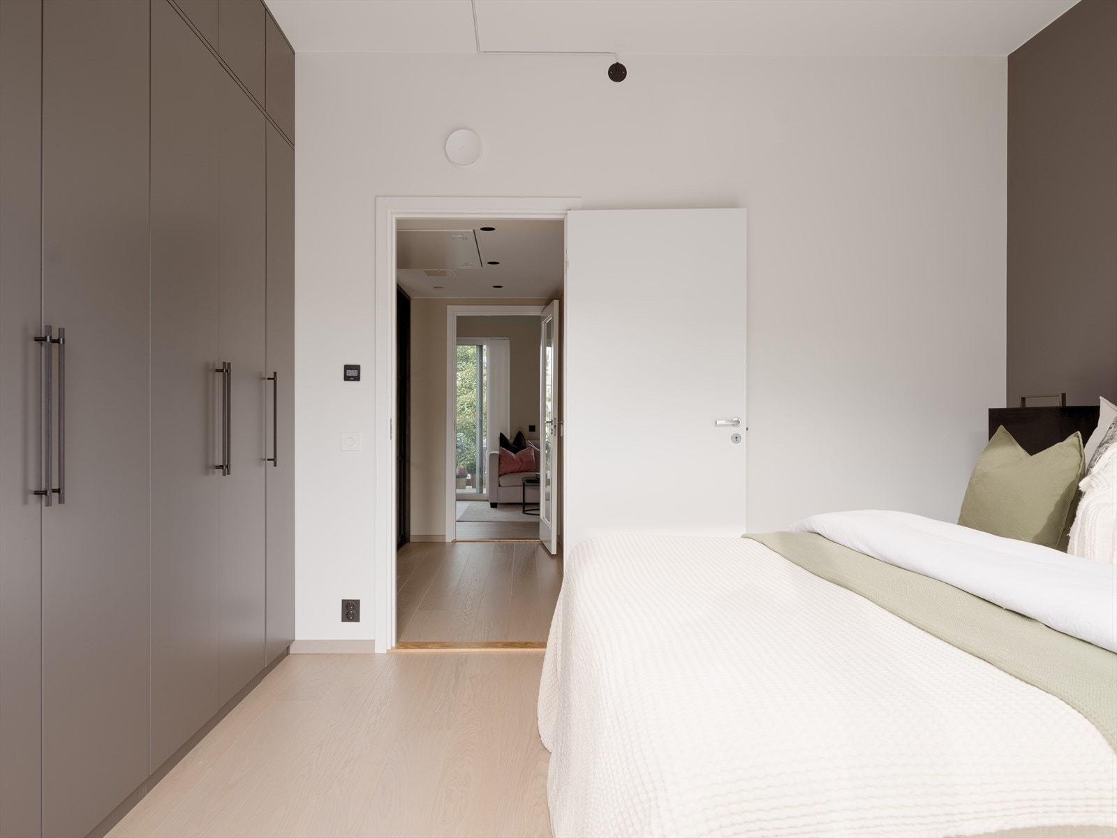 Godt med lagringsplass i et lekkert garderobeskap. Den grå fargen på garderobeskapet som matcher fargen på den parallelle veggen, skaper en delikat kontrast mot de ellers hvite veggene. Galleribilde