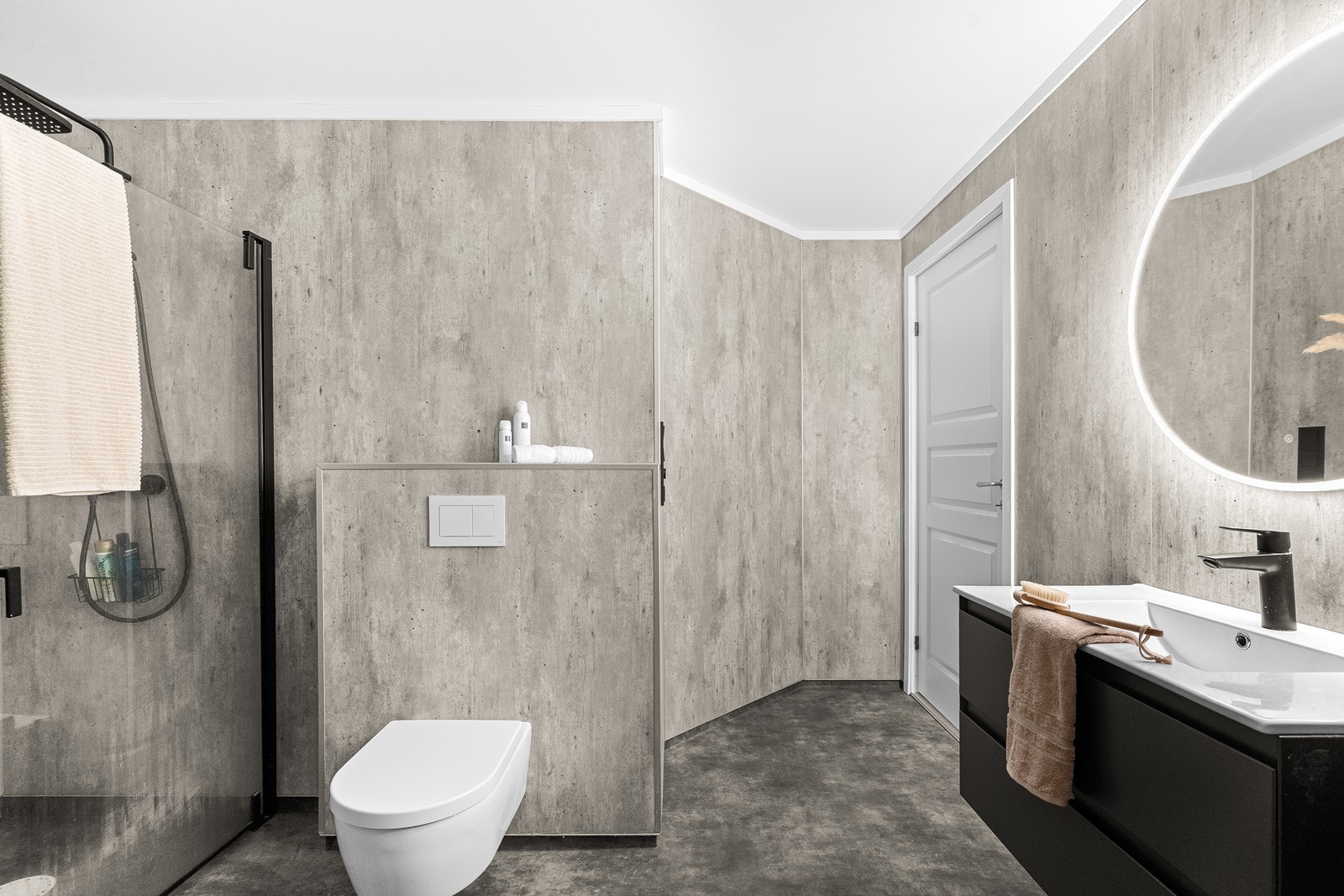 Moderne baderom med dusjhjørne i glass og stilrene sorte detaljer. Vegghengt toalett og praktisk innredning med skuffer for god oppbevaring. Opplegg for vaskemaskin og tørketrommet. Galleribilde