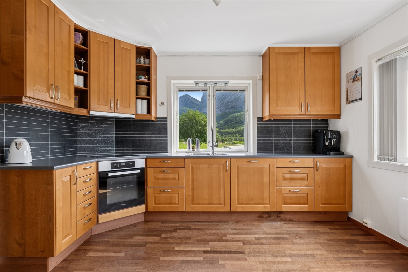 Kjøkkenet står med åpen løsning mot stuen, innredning med heltre profilerte fronter, laminat benkeplate og nedfelt servant. Galleribilde