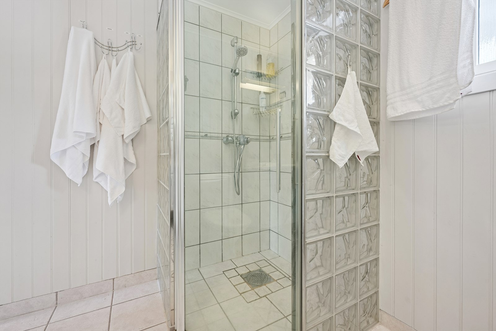 Dusjhjørne med vegger i glassbyggerstein og glassdør. Galleribilde