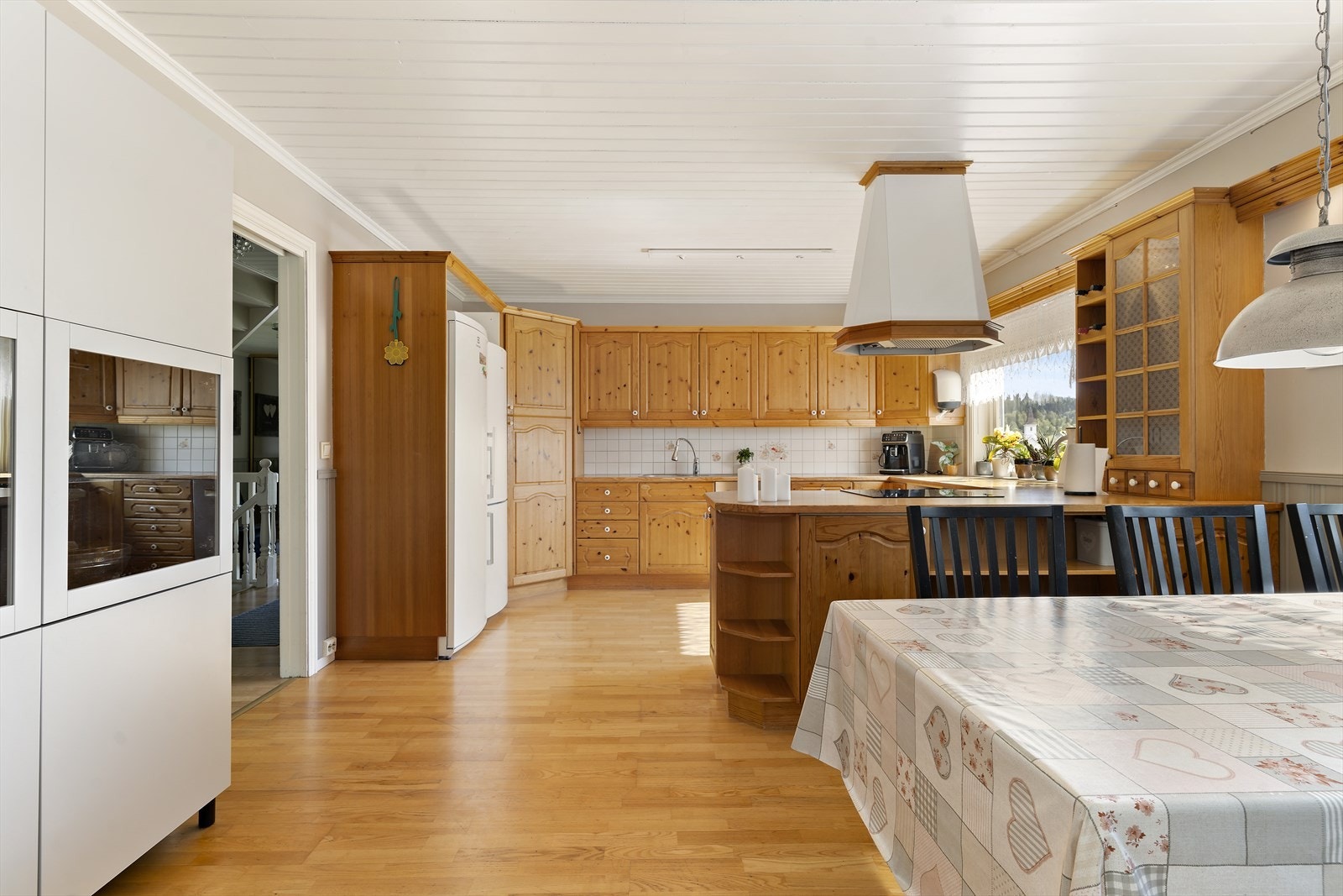 Stort og innholdsrikt kjøkken med rikelig benk- og skapplass. Innredningen har profilerte fronter av type furu, levert av Nygårds trevarefabrikk AS. Benkeplaten er av laminat. Galleribilde