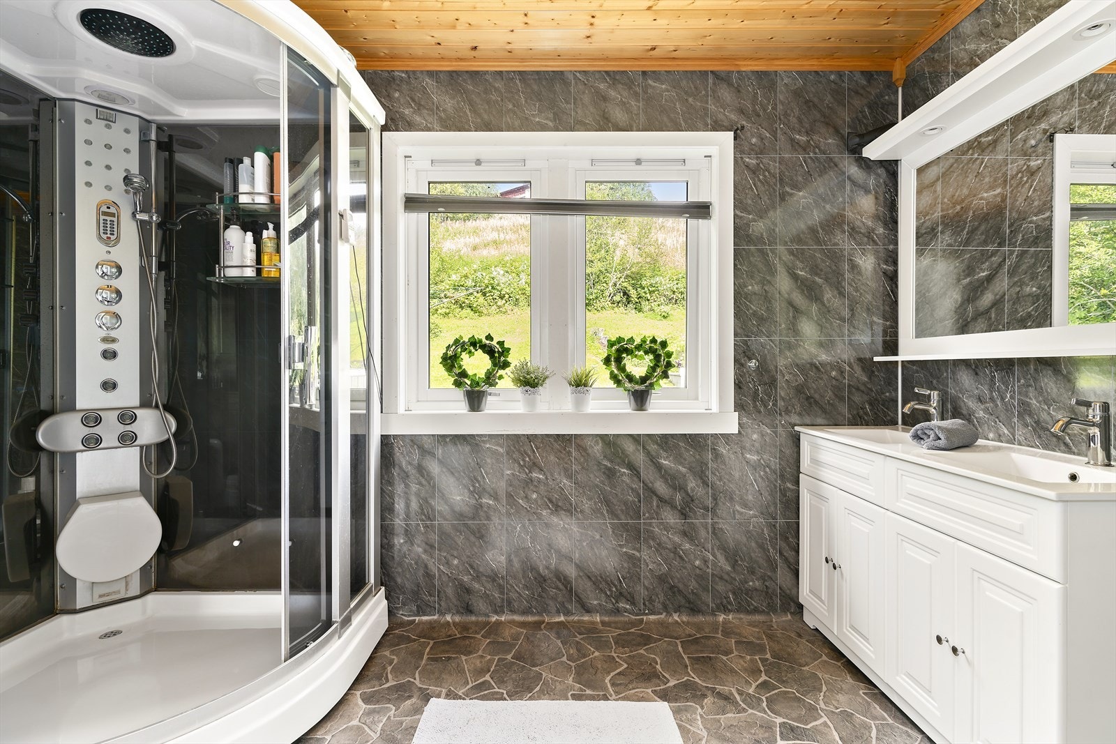 Badet i hovedetasjen er fra ca. 2007. Røropplegg utført av Comfort Mosjøen. Badet er av romslig størrelse og har innredning med 2 nedfelte servanter, veggmontert toalett og dusjkabinett. Galleribilde