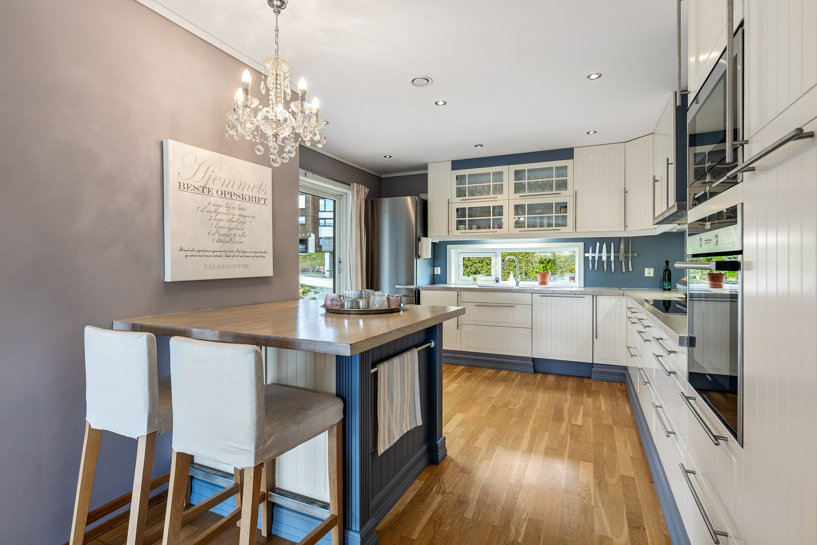 Integrert oppvaskmaskin, stekeovn og platetopp. Vegghengt ventilator over platetopp. Vegg og himlingsflater i malte flater. Gulvflater belagt med parkett. Fliser mellom kjøkkenbenk og overskap. Galleribilde