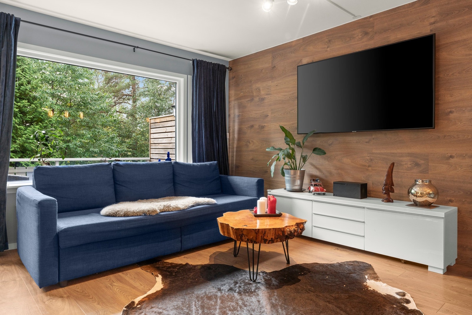 Den romslige stuen gir plass til en koselig sofakrok med store vindusflater som gir flott utsyn mot grønne omgivelser. Galleribilde