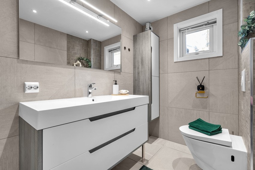 Flislagt bad med stilren innredning, toalett og dusjløsning Galleribilde