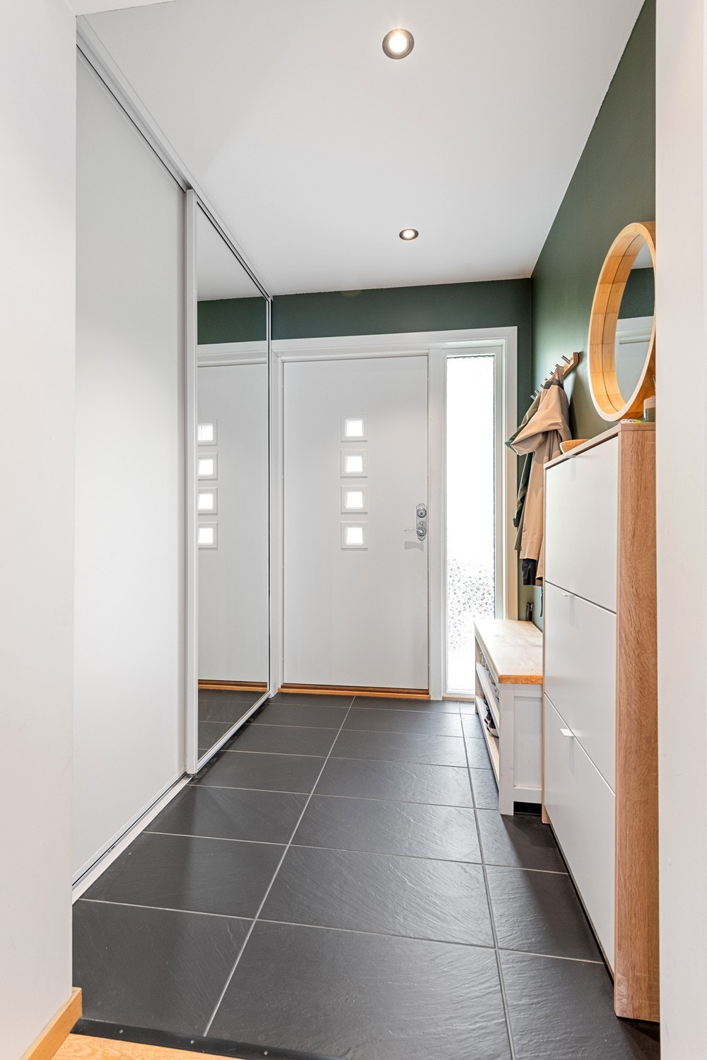Velkommen til en innbydende entré med moderne detaljer, speilskyvedørsgarderobe og flislagt gulv som gir et stilrent førsteinntrykk. Galleribilde
