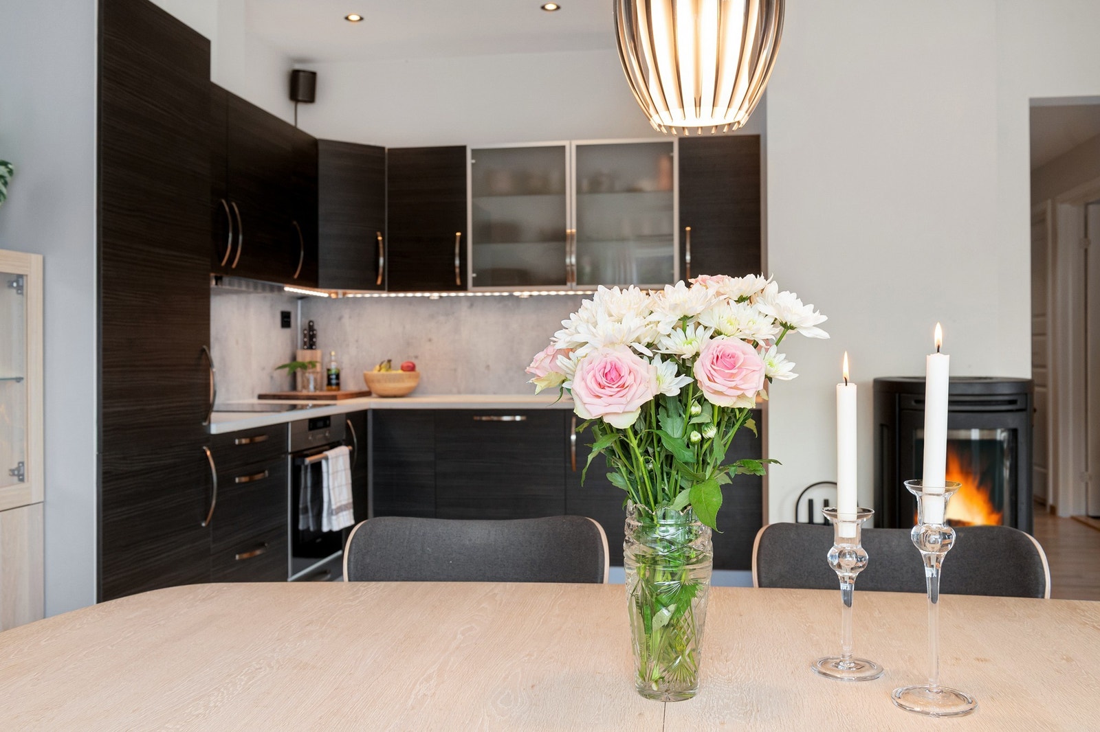 Lyst og moderne kjøkken med stilren belysning og peis. Perfekt for hyggelige stunder og måltider med familie og venner. Galleribilde