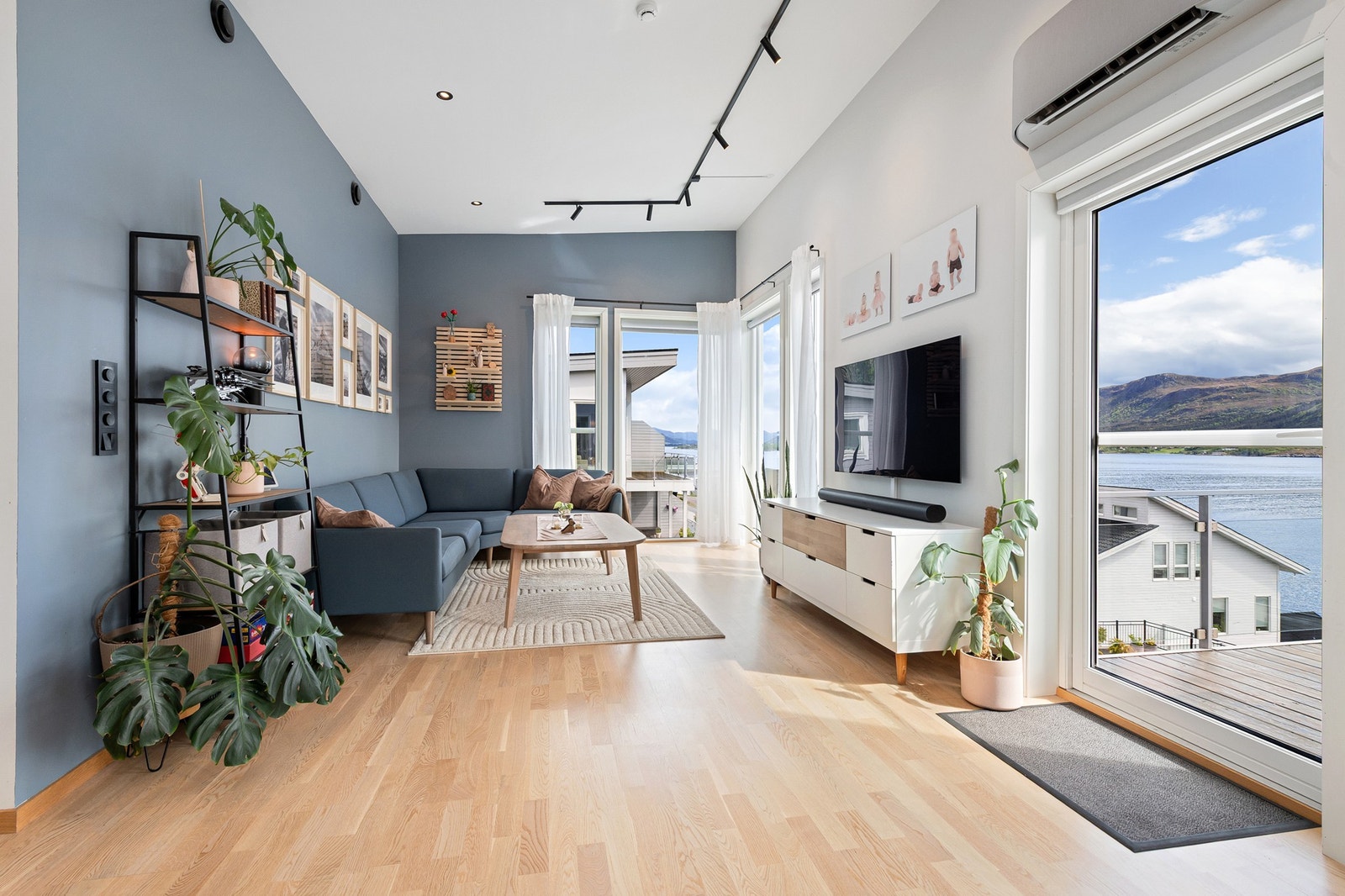 Lys og moderne stue med store vinduer som gir fantastisk utsikt over fjorden og fjellene utenfor. Galleribilde