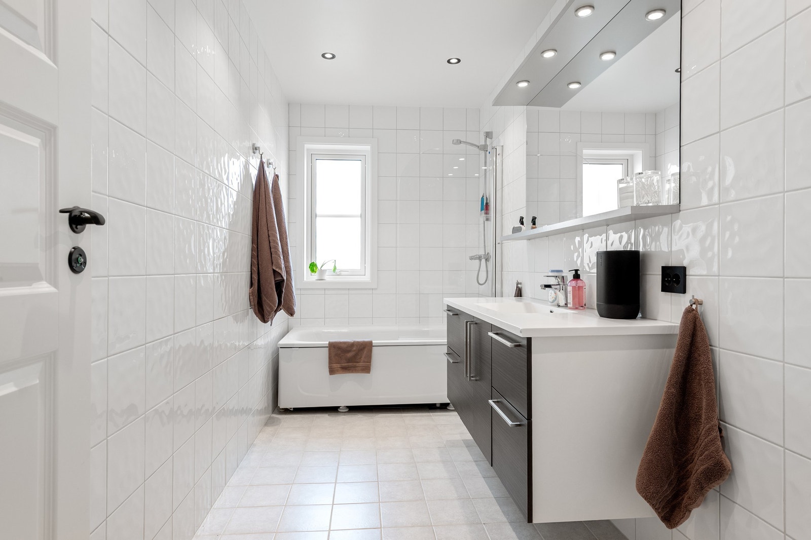 Lyst og moderne bad med dusj og badekar. Fliser på vegger og gulv, stilrent design med gode oppbevaringsløsninger. Galleribilde