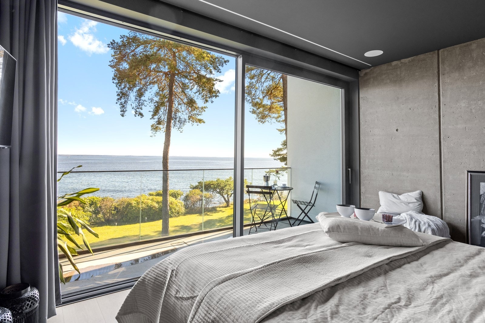 Hele veggen mot havet består av vindusflater fra gulv til tak, i hele rommets bredde. Halve veggen kan skyves til side, og leder ut til egen balkong med rekkverk bestående av kun glass og diamantlipt betongdekke. Galleribilde