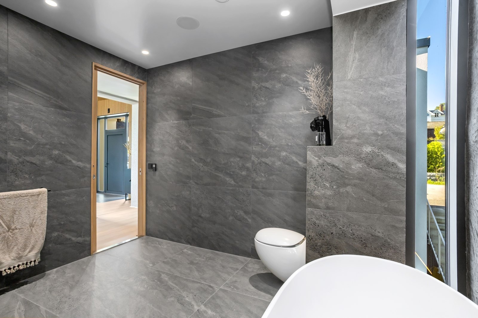 Badet er innredet med moderne storformatfliser i lekre gråtoner på gulvet og på veggene. Dette badet, som byr på en høy dose "hverdagsluksus", kombinerer funksjonalitet med luksuriøse detaljer. Galleribilde