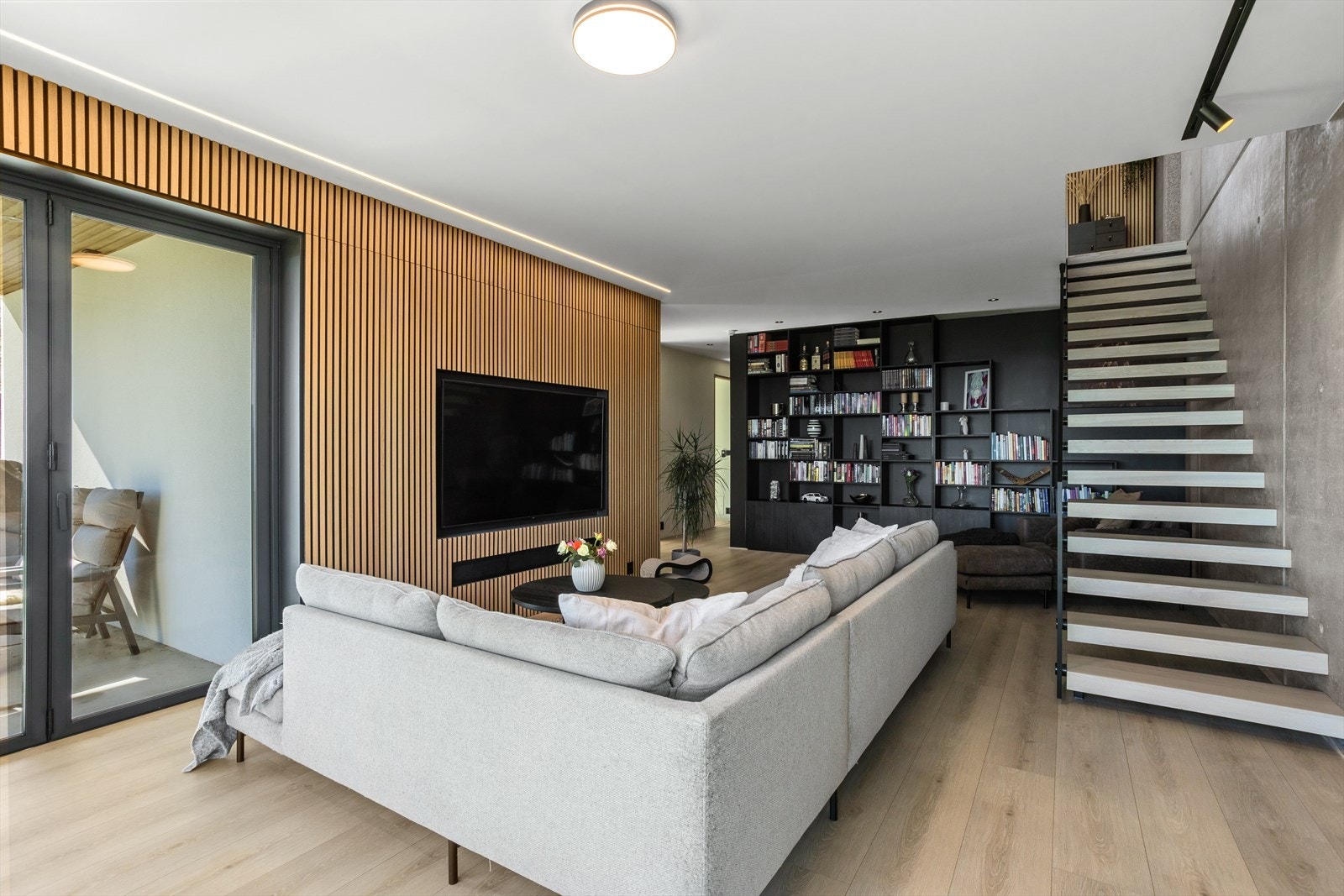 Stuens utforming gir plass til å møblere rommene slik du selv ønsker, med god plass til sofa-/loungegrupper og lenestoler.Det er godt med veggplass å møblere mot. Innerst i rommet er det plassbygget bokhyller og skap fra gulv til tak. Galleribilde