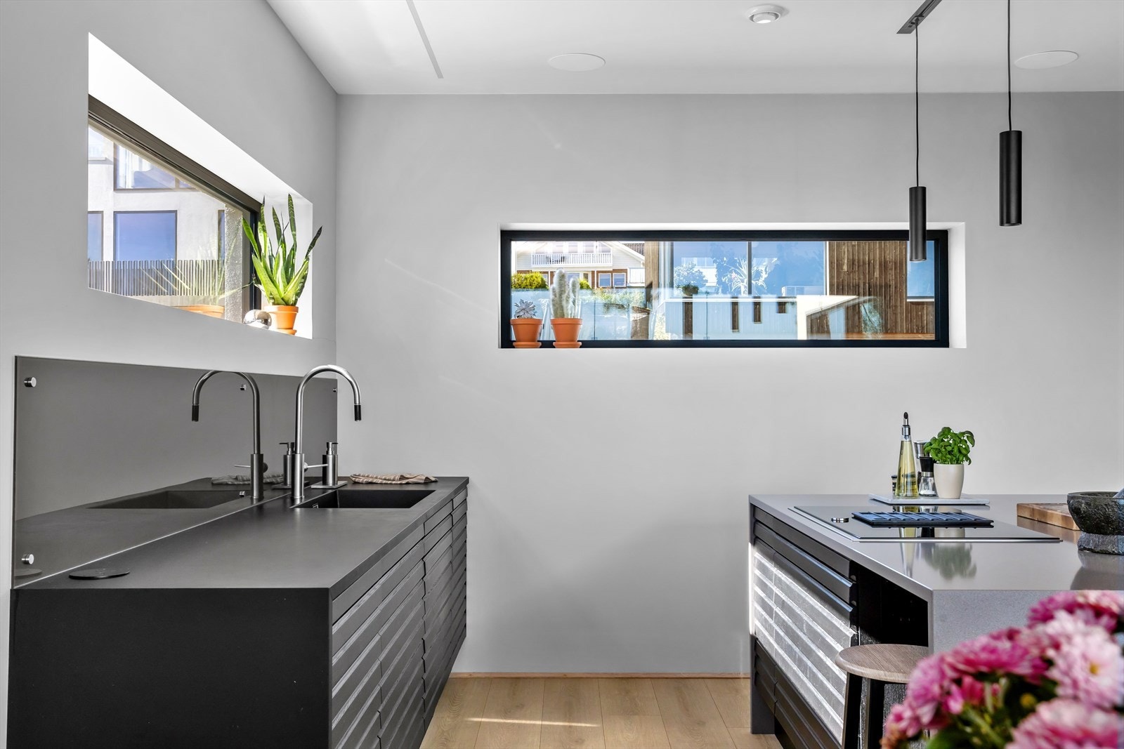 Ved stor integrert kjøkkenøy kan man tilberede måltider samtidig som man har sosial nærkontakt og kan holde samtalen i gang med resten av familien og venner som oppholder seg i stue-/spisestuensonen i hovedetasjen. Galleribilde