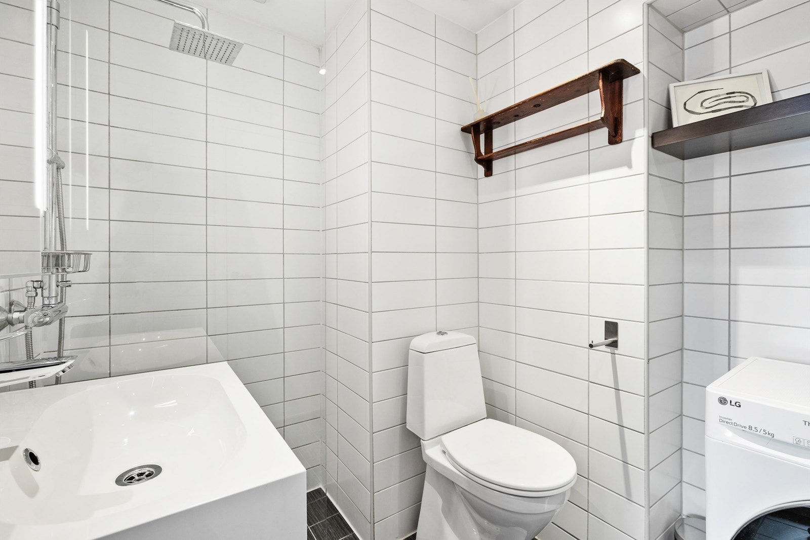 Badet er innredet med gulvstående klosett, servant på servantinnredning, vegghengt speil med belysning og dusjsone med glassdør. Galleribilde