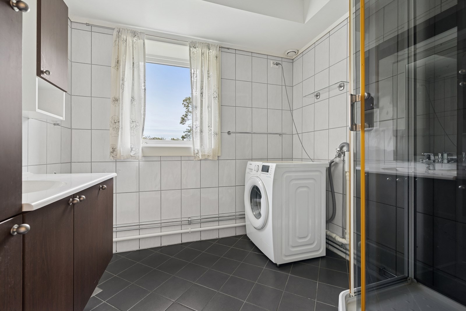 Flislagt bad med dusjhjørne og opplegg for vaskemaskin Galleribilde