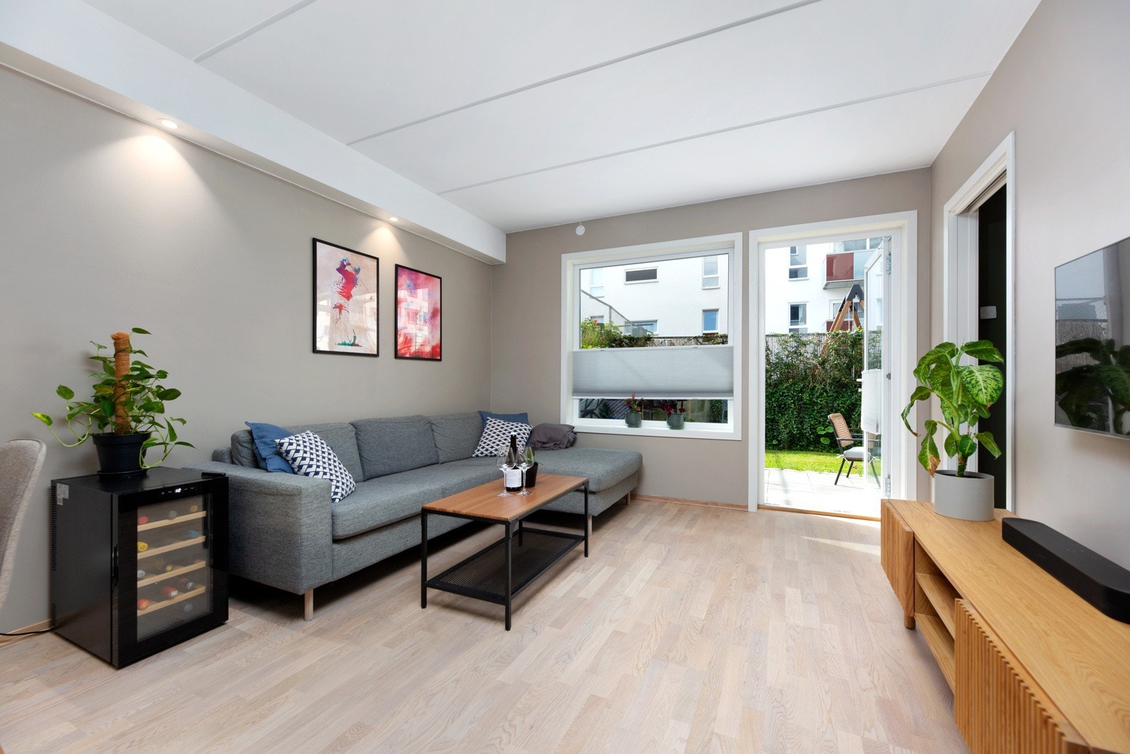 Stuen har store vindusflater som slipper inn rikelig med naturlig lys og skaper en hyggelig atmosfære. Det ble montert plissegardiner ved stuevindu og terrassedør i 2024. Galleribilde