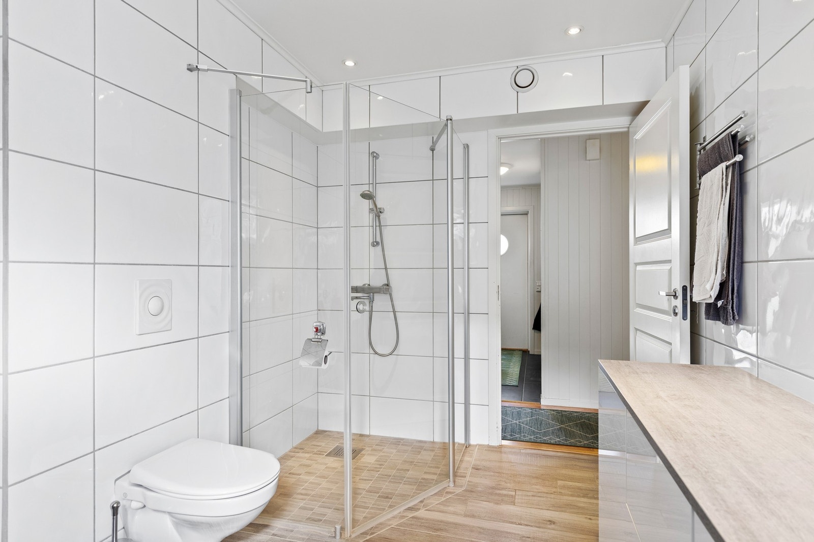 Baderommet er utstyrt med dusjhjørne, mekanisk avtrekk, veggmontert wc, servant og servantskap. Galleribilde