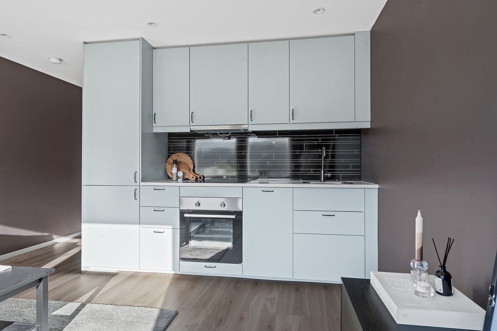 Stuen er åpen mot kjøkken med integrerte hvitevarer Galleribilde