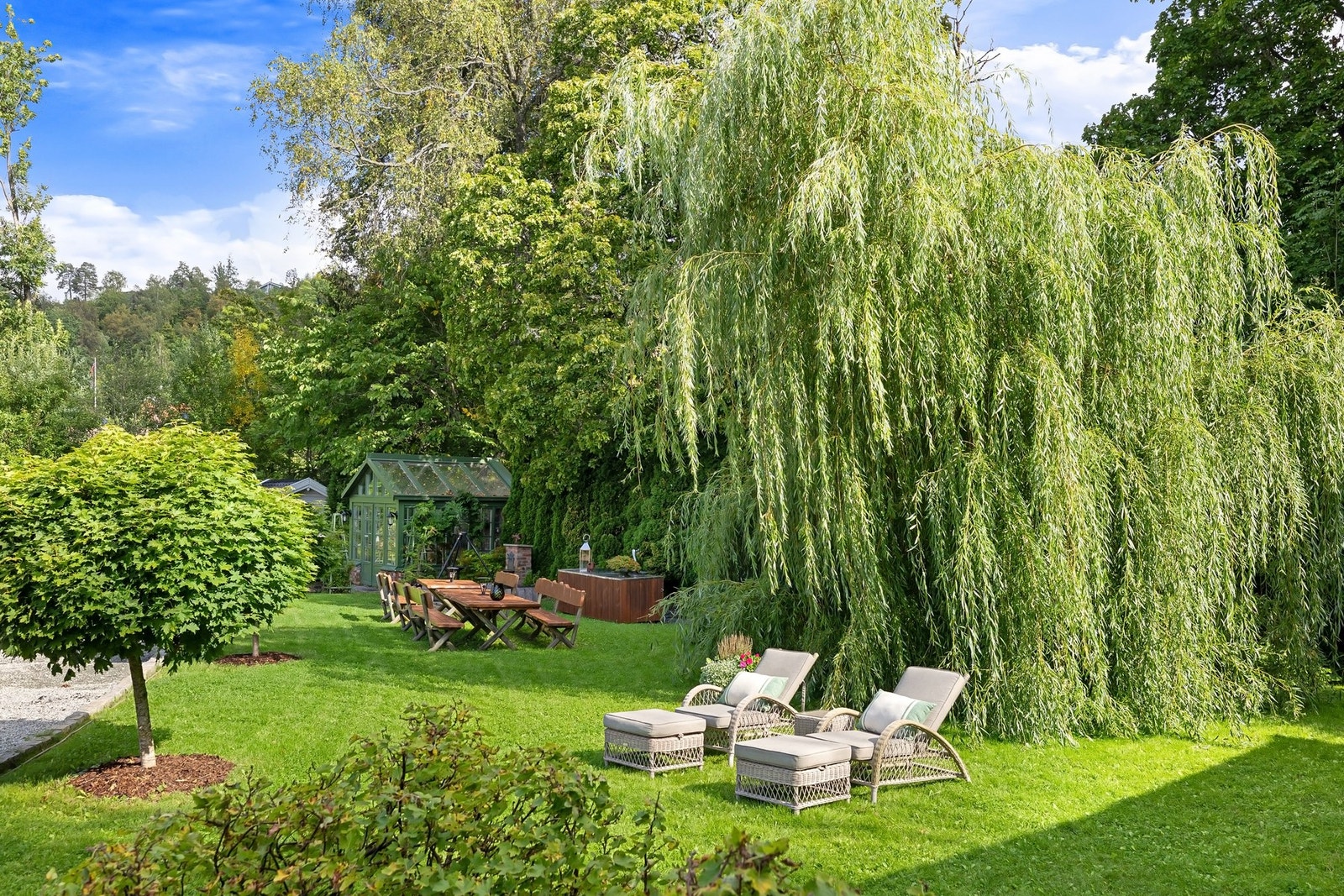 Vakker hage med skyggefulle trær og solrike sitteplasser. Galleribilde