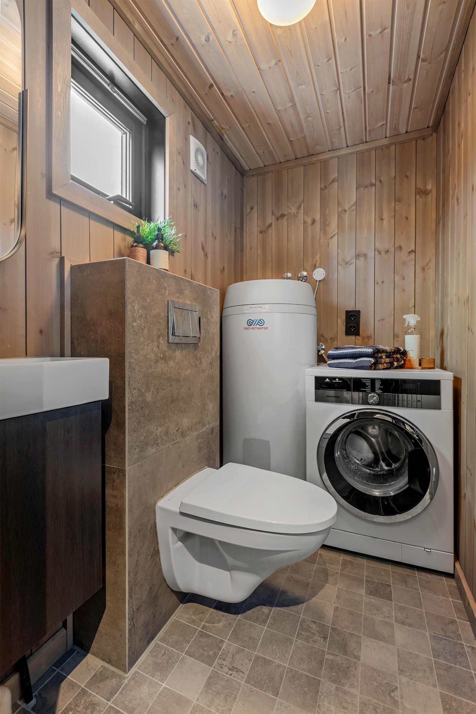 Hytta har også et kombinert toalett - og vaskerom, som er innredet med et veggmontert toalett, servant, vaskemaskin og varmtvannsbereder. Galleribilde