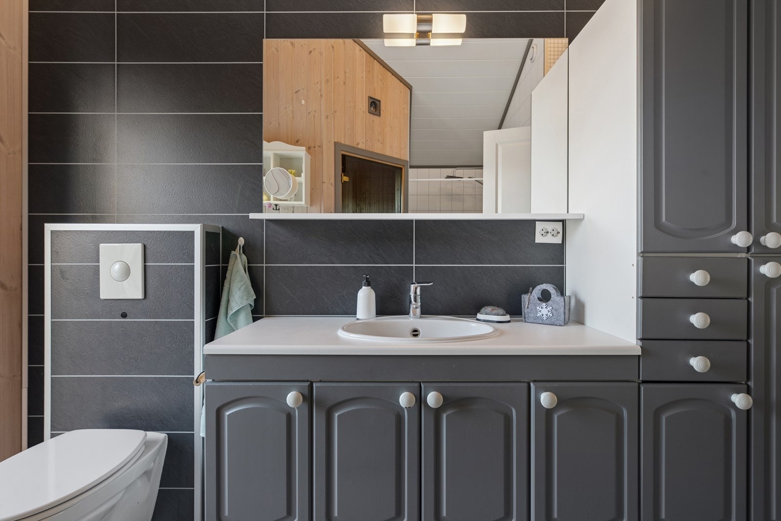 Badet er utstyrt med innredning med nedfelt servant, veggmontert toalett og dusjnisje med forheng. Galleribilde