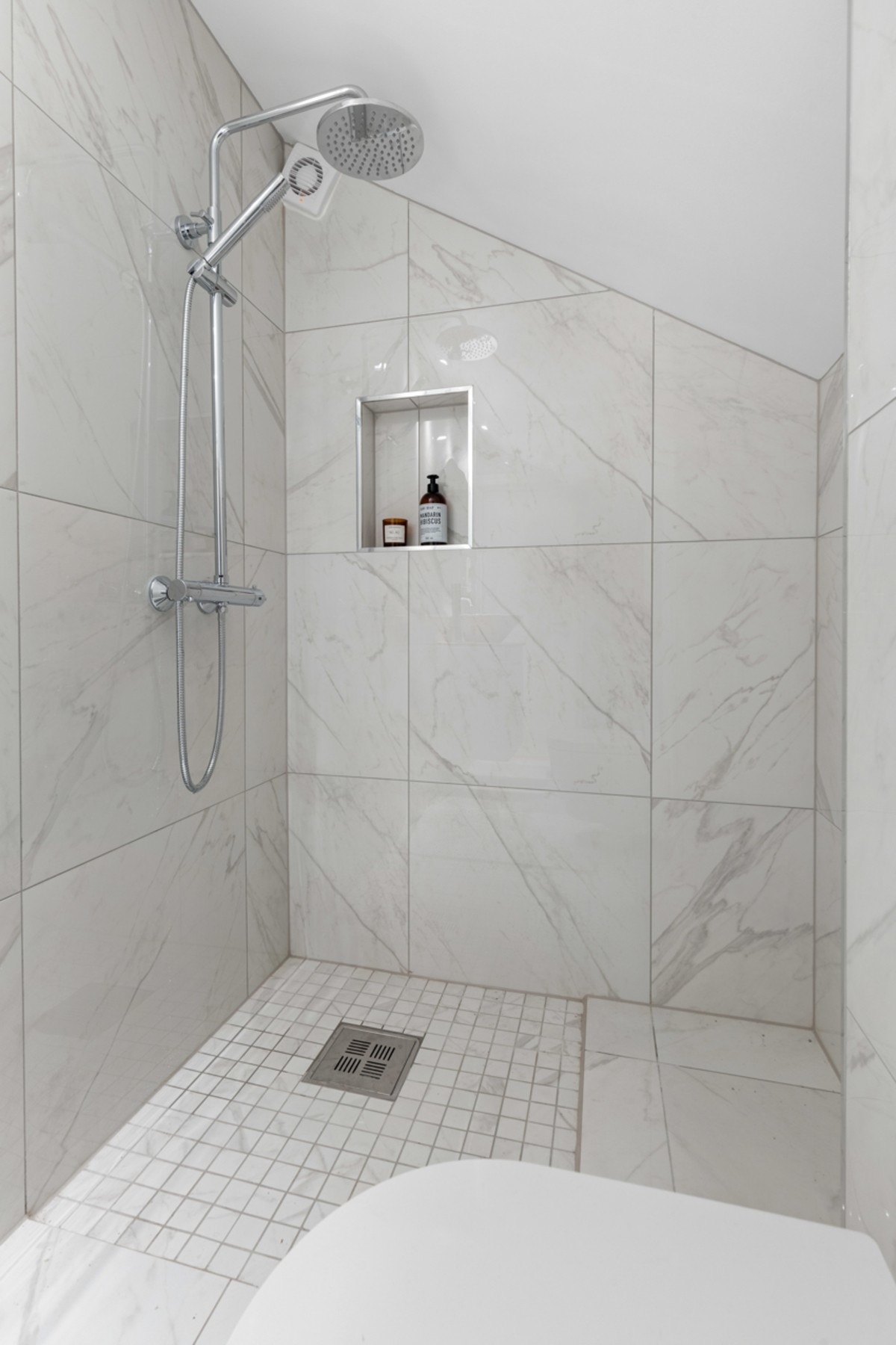 Badet har gulvvarme, downlights, et rundt speil, vegghengt toalett og et nedsenket dusjhjørne. Sistnevnte har regnfallsdusj og en innfelt hylle. Galleribilde