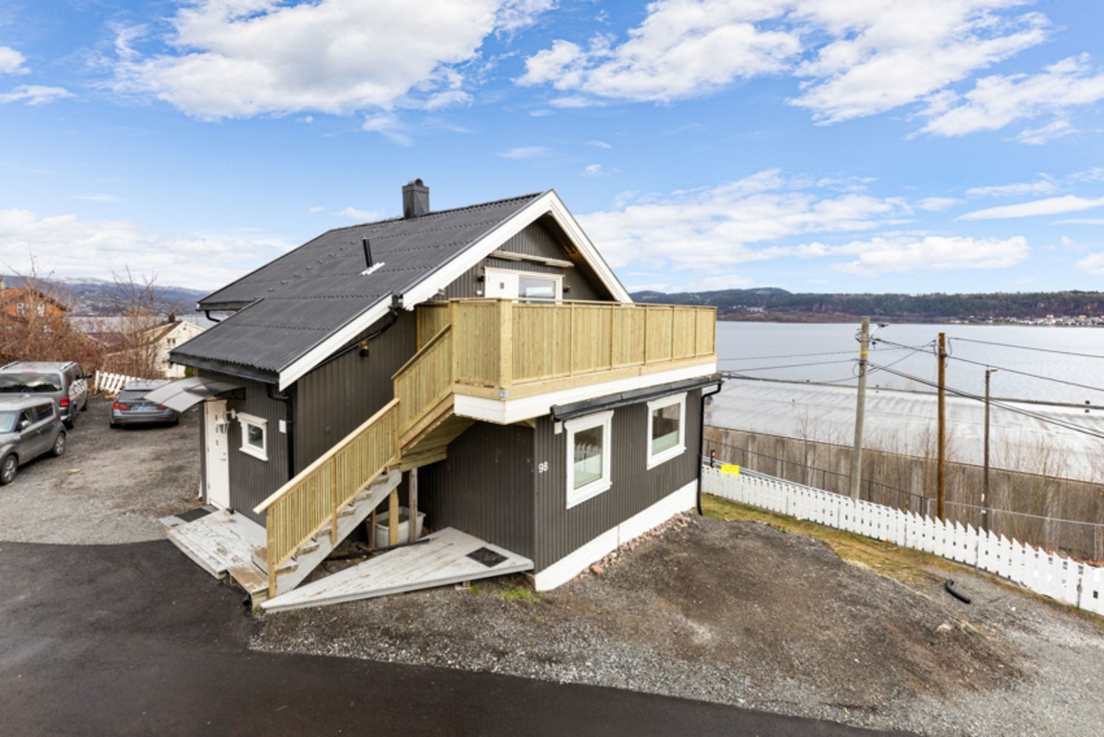 Fra gårdsplassen er det trapp opp til en adkomstveranda, hvor det er en hvit ytterdør med glassfelt fra 2022. Galleribilde