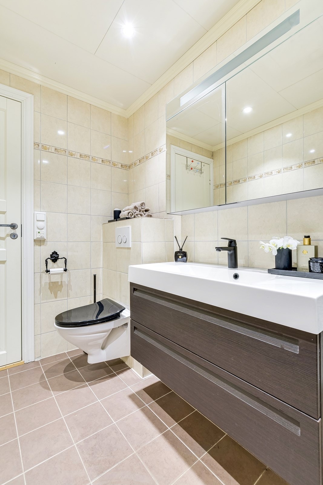 Bred hvit servant med sort underskap og speilskap med overlys på vegg Galleribilde