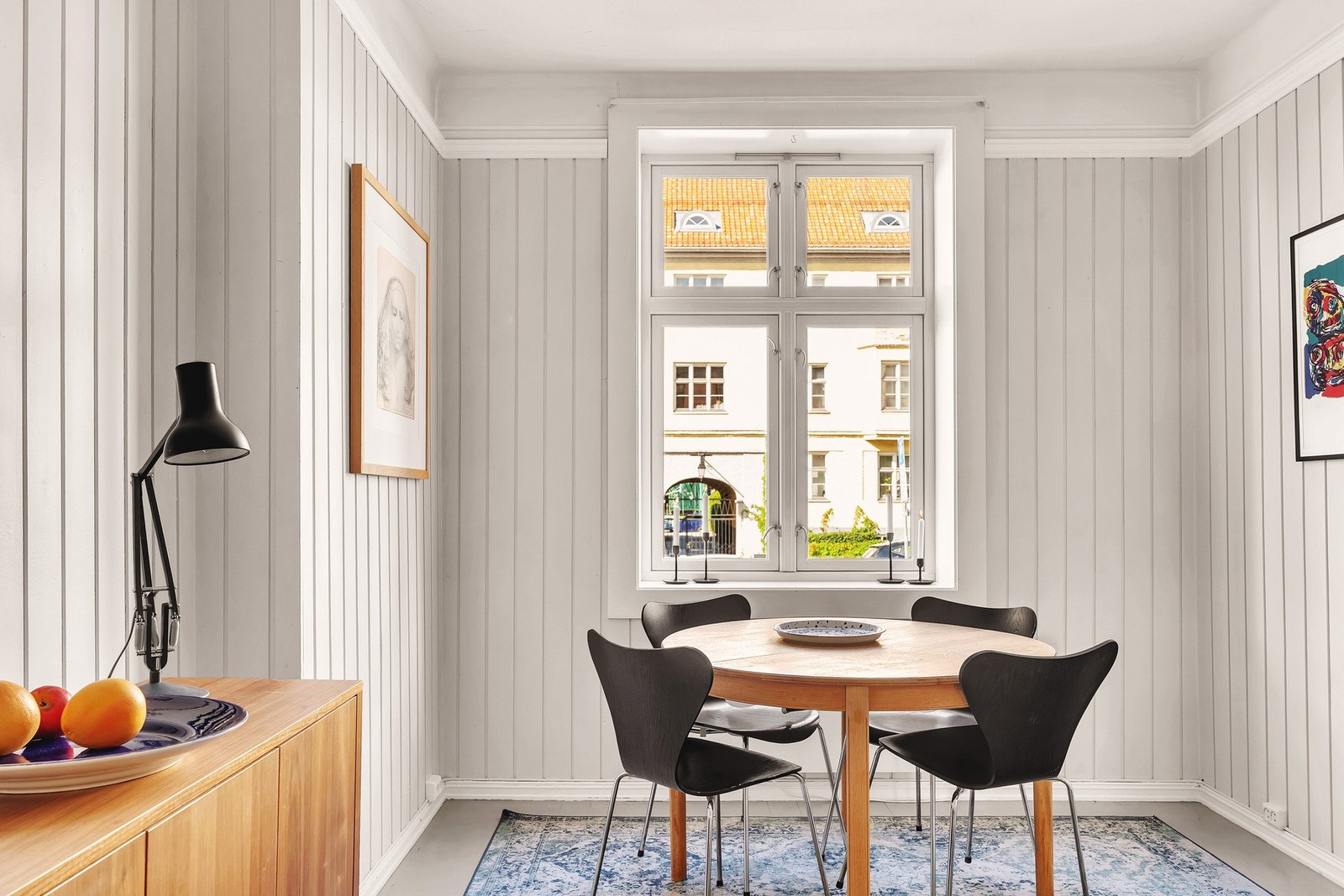 De lyse panelveggene gir rommet en klassisk og tidløs karakter, mens store vinduer slipper inn rikelig med dagslys. Galleribilde