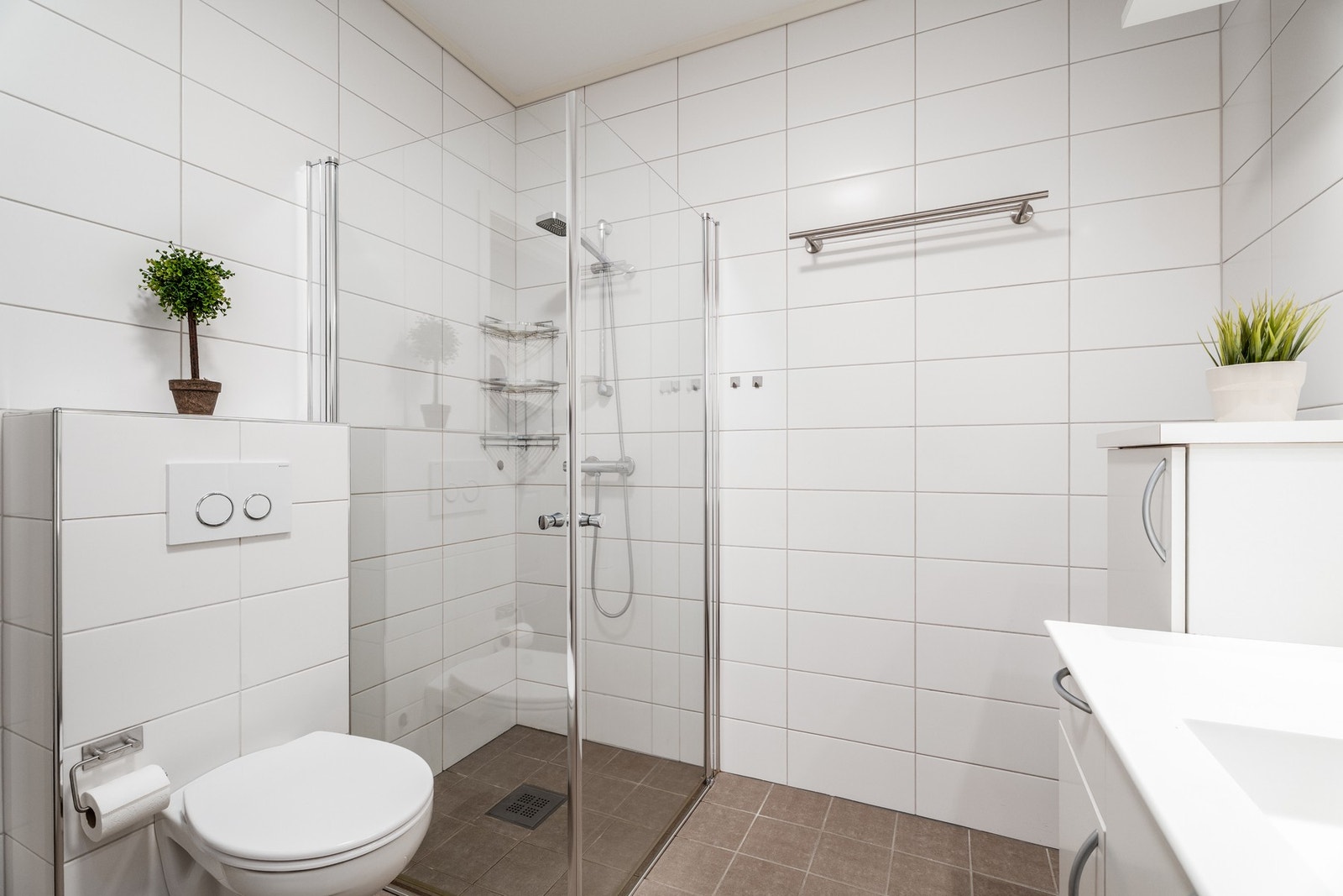 Lyst og flott flislagt bad med lekkert dusjhjørne med glassdører Galleribilde