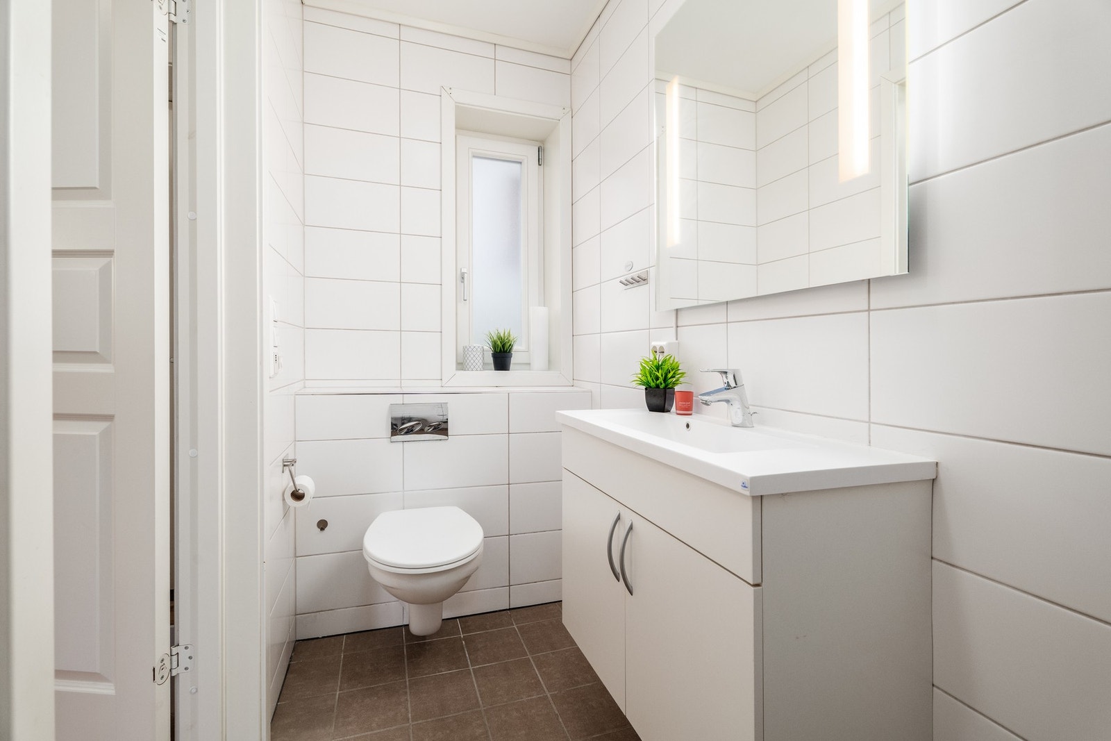 Pent og lyst flislagt bad med vegghengt innredning og wc. Galleribilde